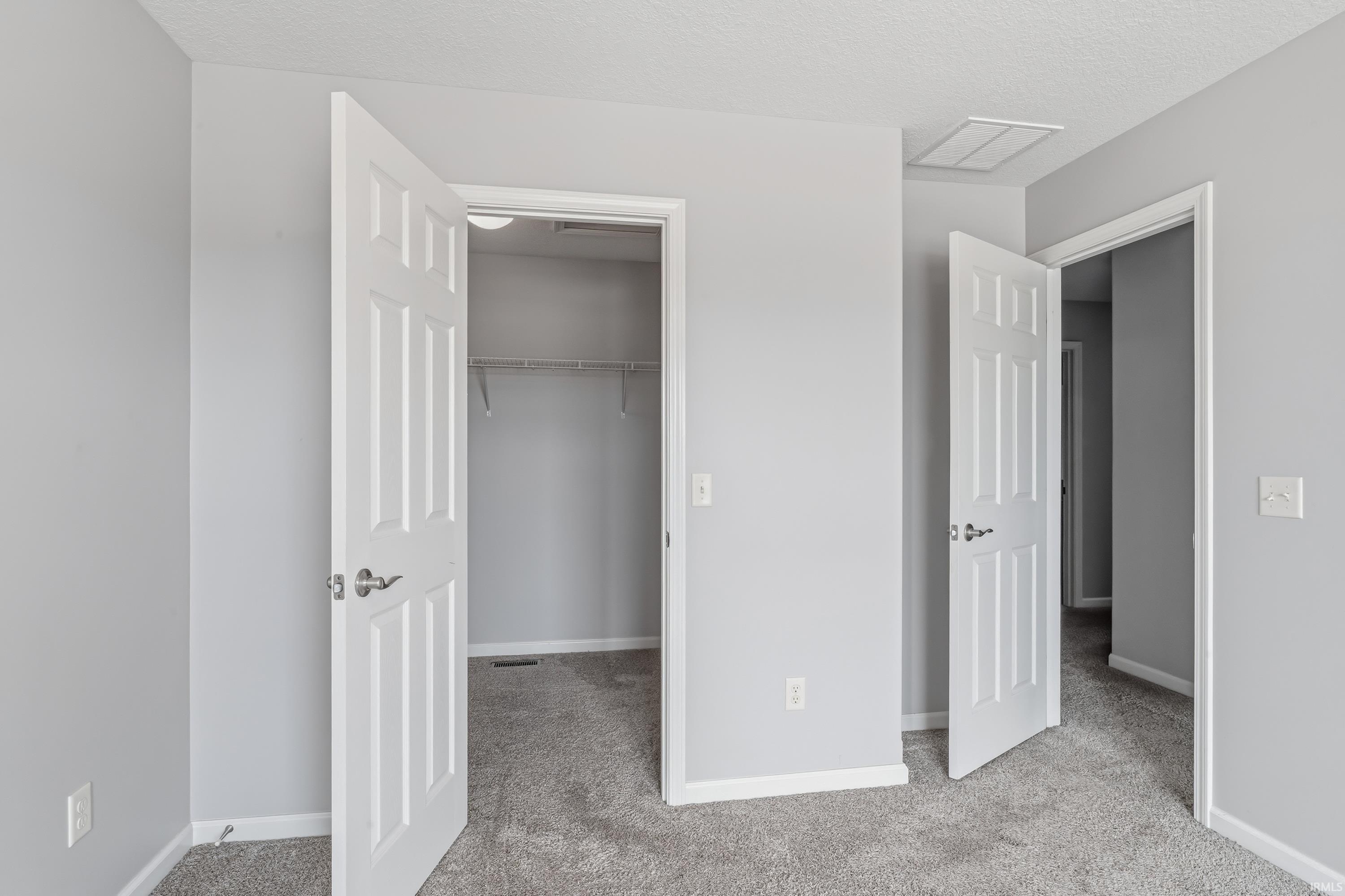 Interior space featuring light gray wall paint, white trim, and gray carpet flooring