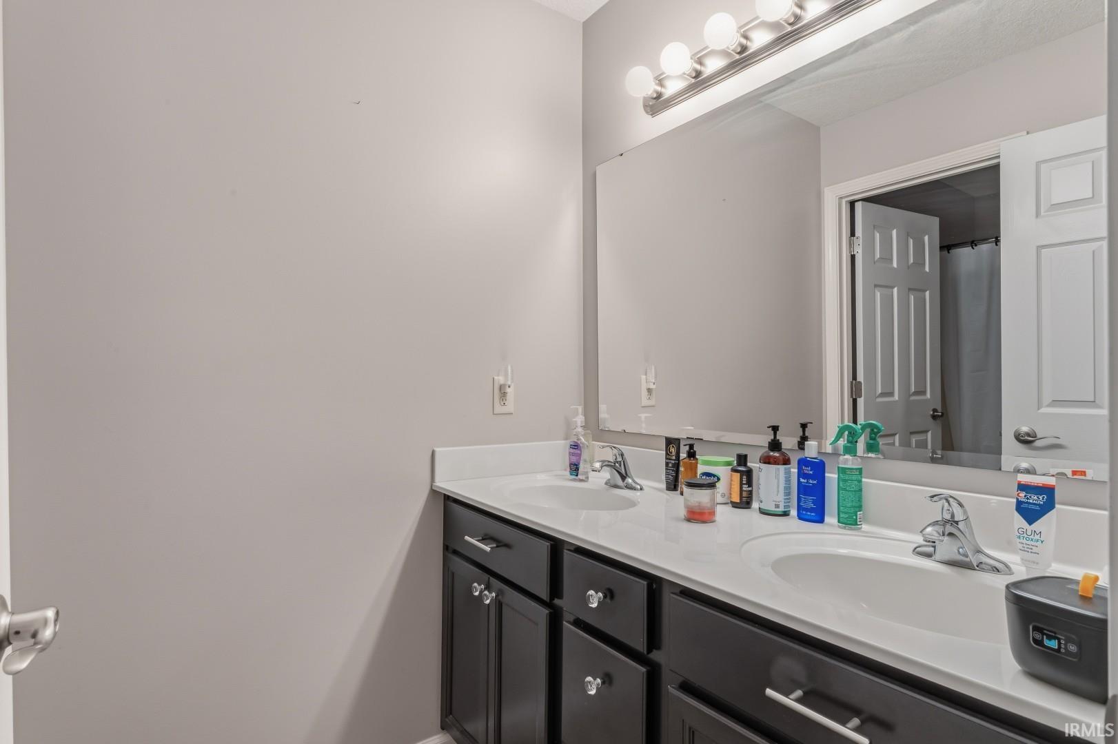 Double vanity featuring dark cabinetry, white countertops, dual undermount sinks, and chrome faucets