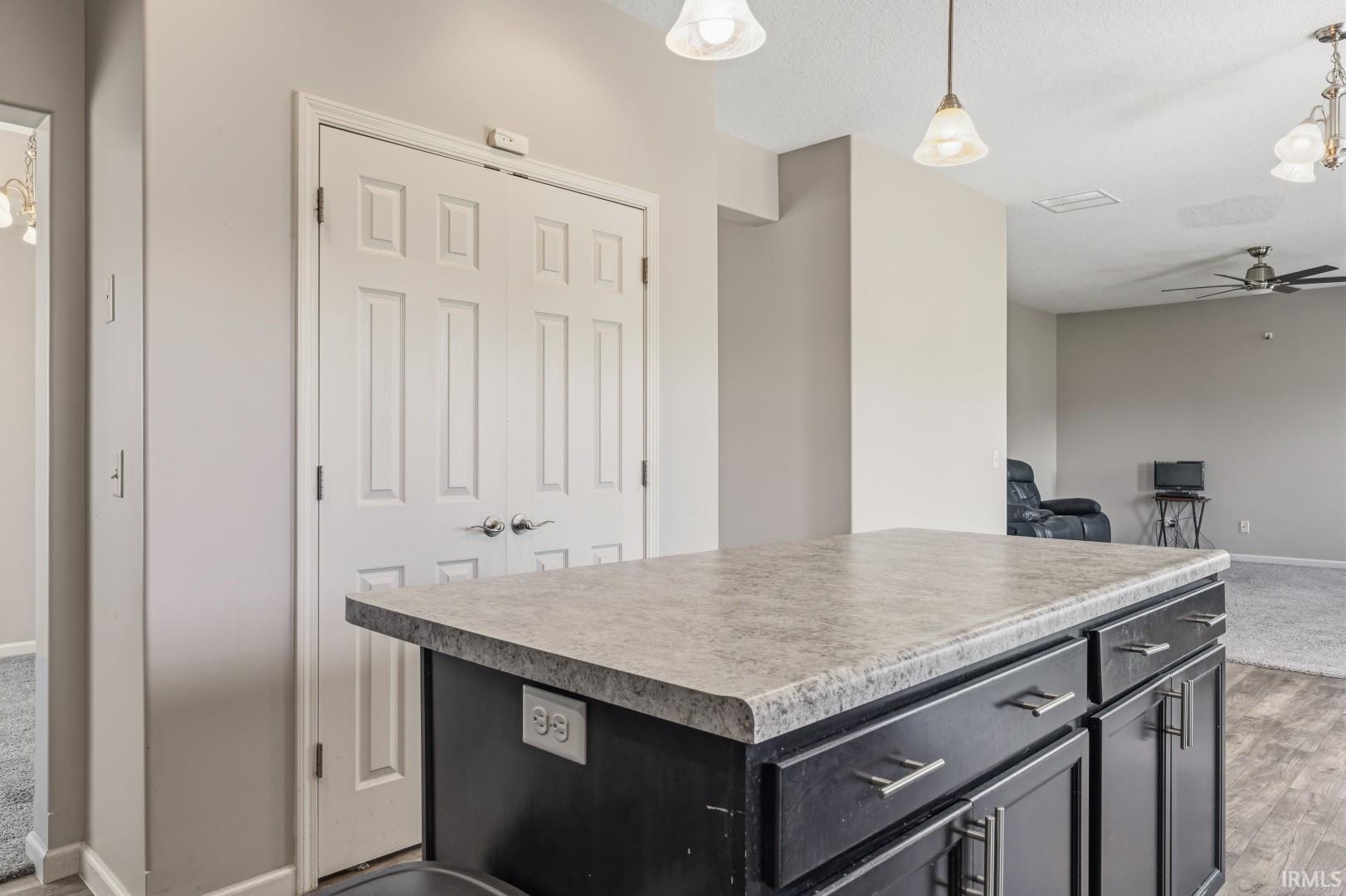 Kitchen island featuring a laminate countertop, dark wood-finish cabinetry, and brushed nickel hardware