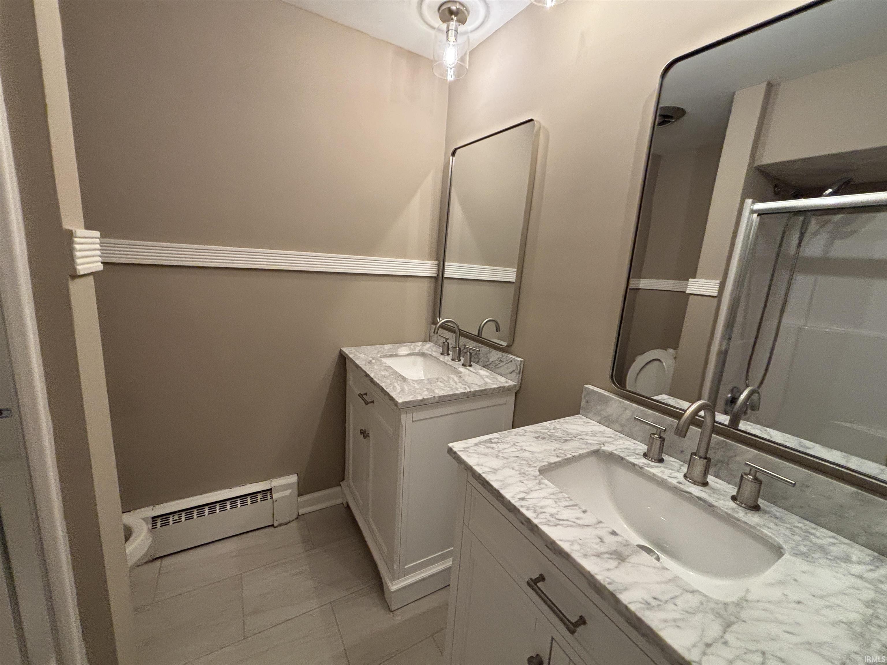 Dual vanity bathroom featuring stone countertops, undermount sinks, brushed nickel fixtures, and individual framed mirrors