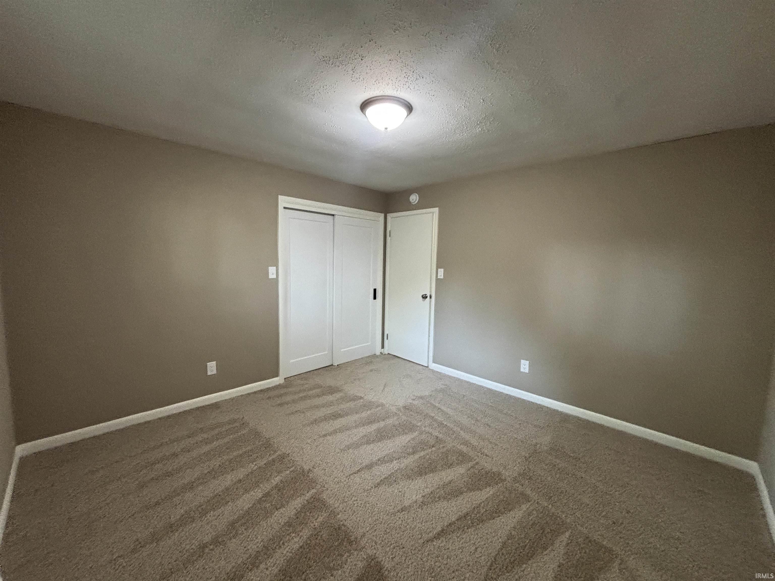 Interior room featuring neutral-toned walls, patterned carpet flooring, and white trim