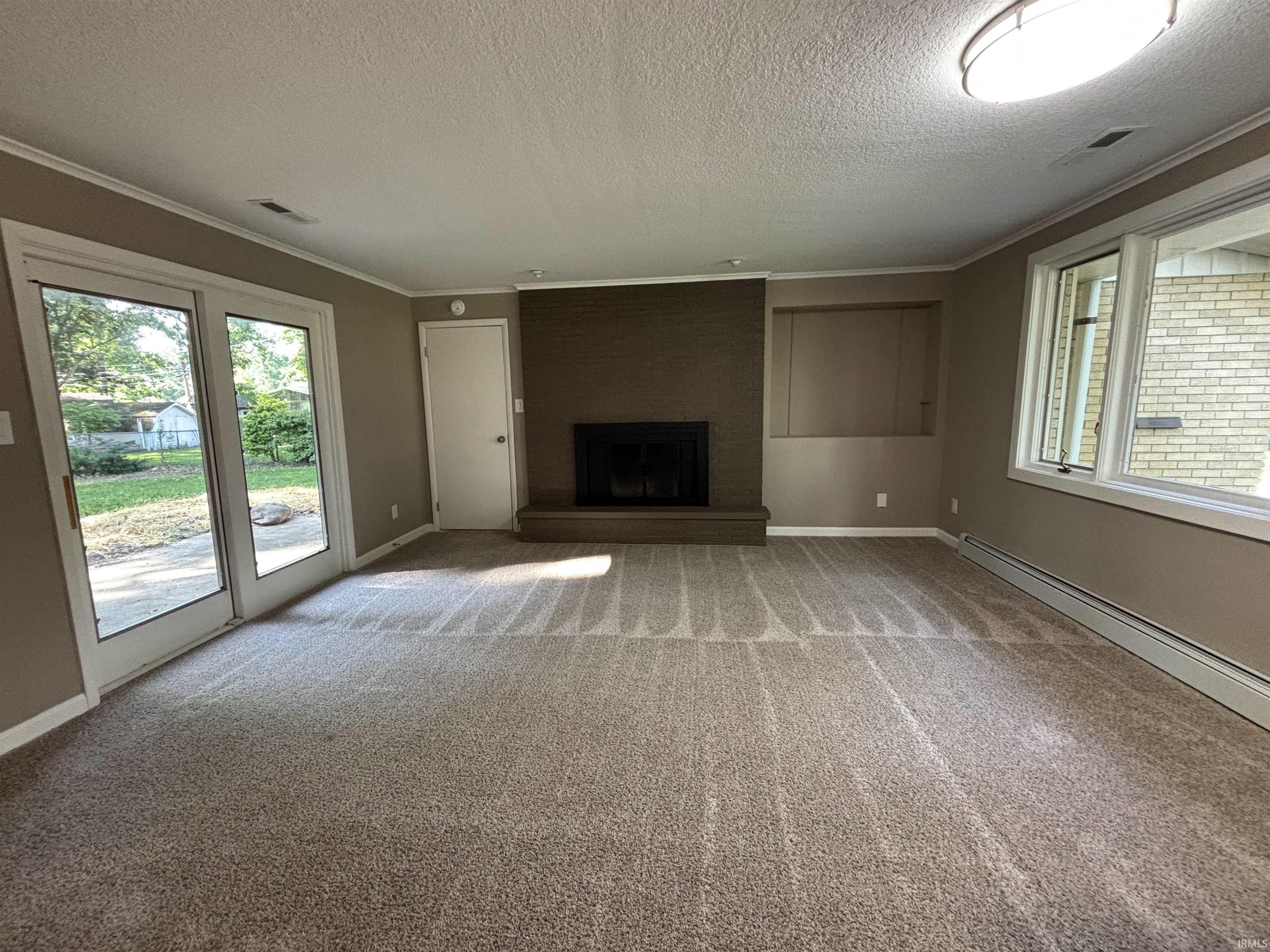 Carpeted living area featuring a brick-surround fireplace, sliding glass doors to the exterior, and multiple windows