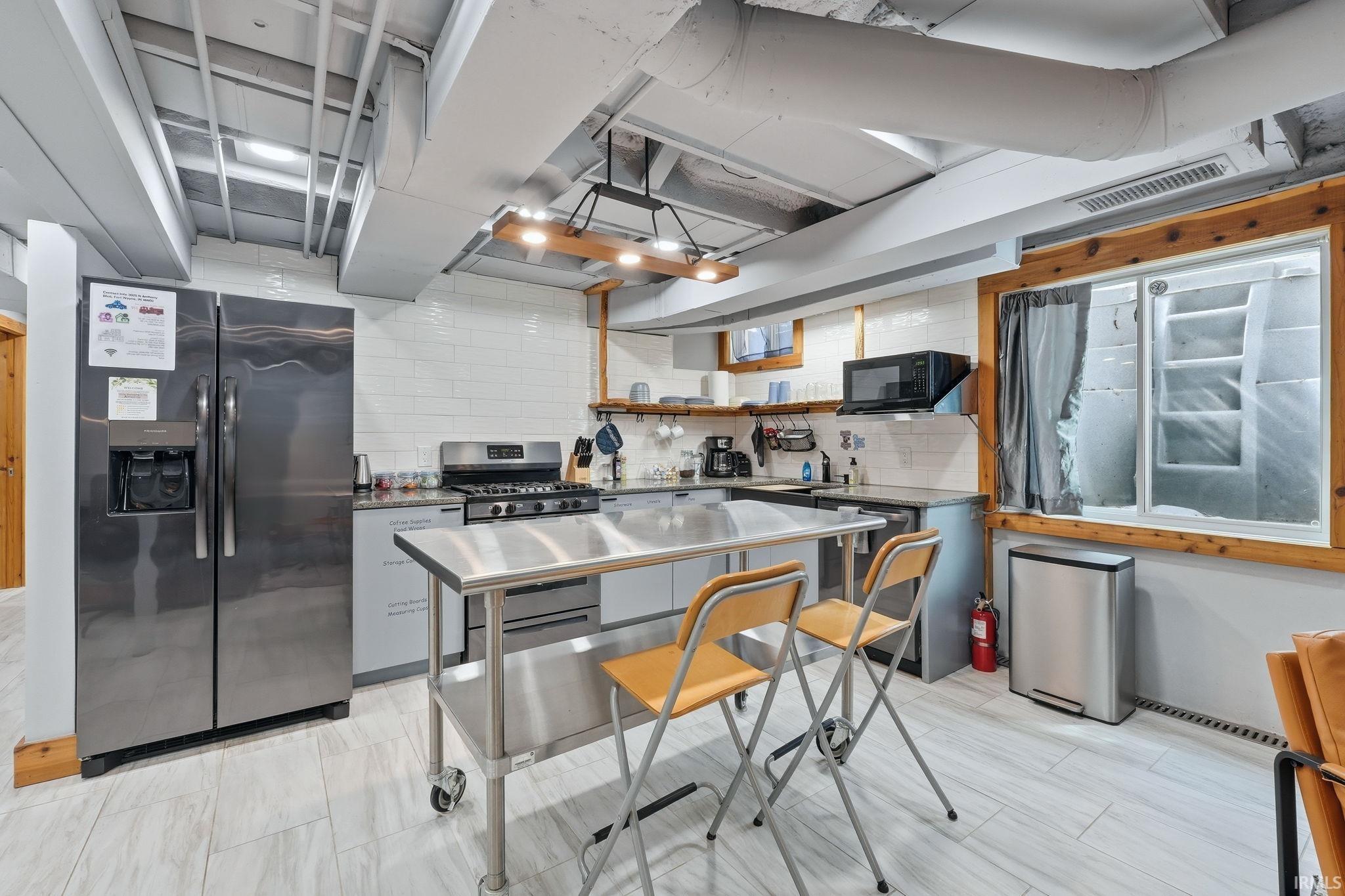 Kitchen area featuring a stainless steel refrigerator, gas range, and microwave