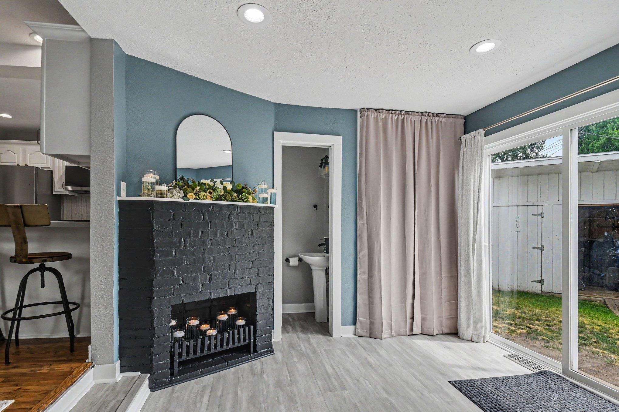 Living area featuring a painted brick fireplace, light wood-finish flooring, recessed lighting, and a sliding glass door