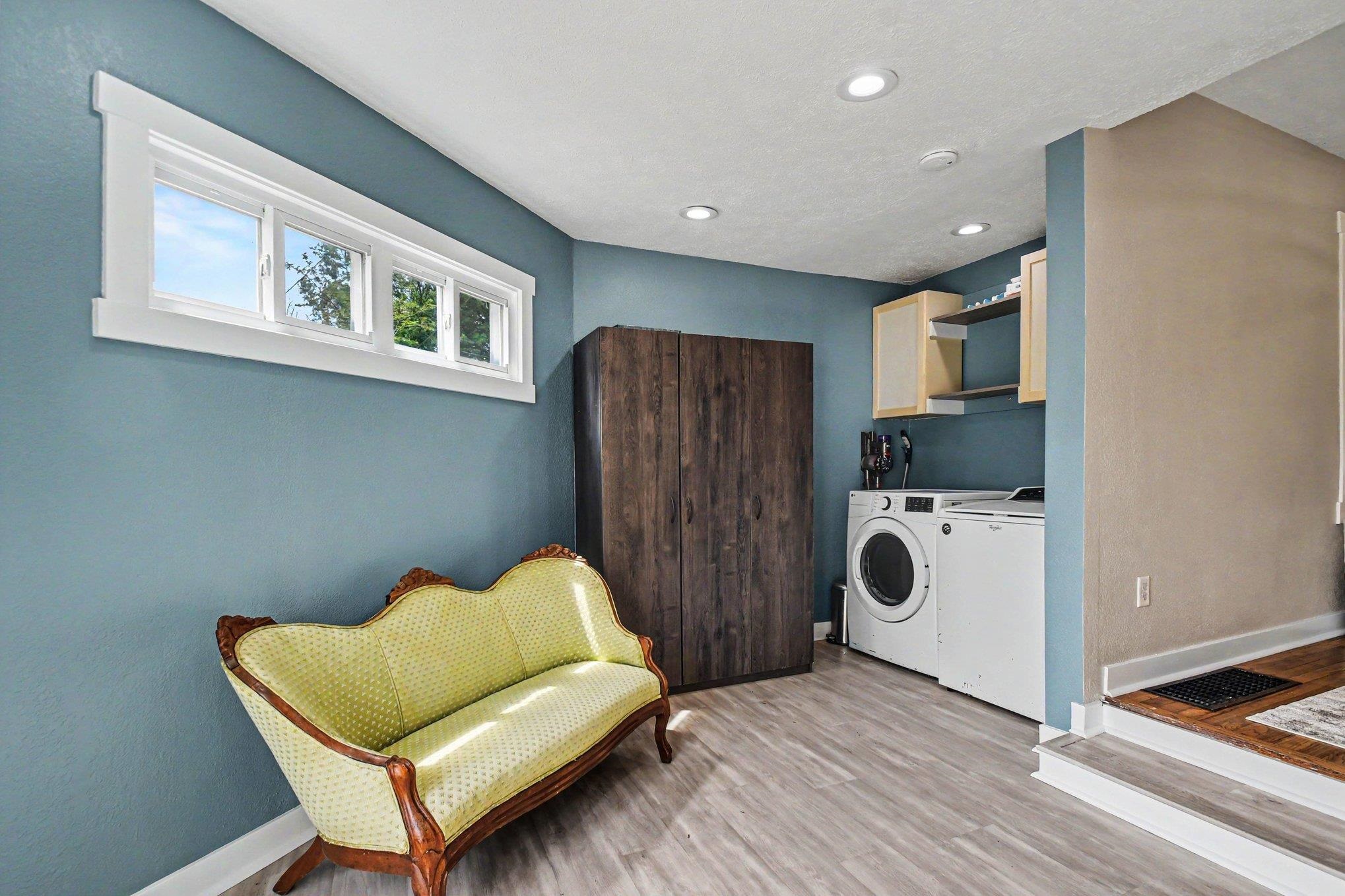 Laundry area featuring light wood-finish flooring, recessed lighting, and a horizontal window with white trim