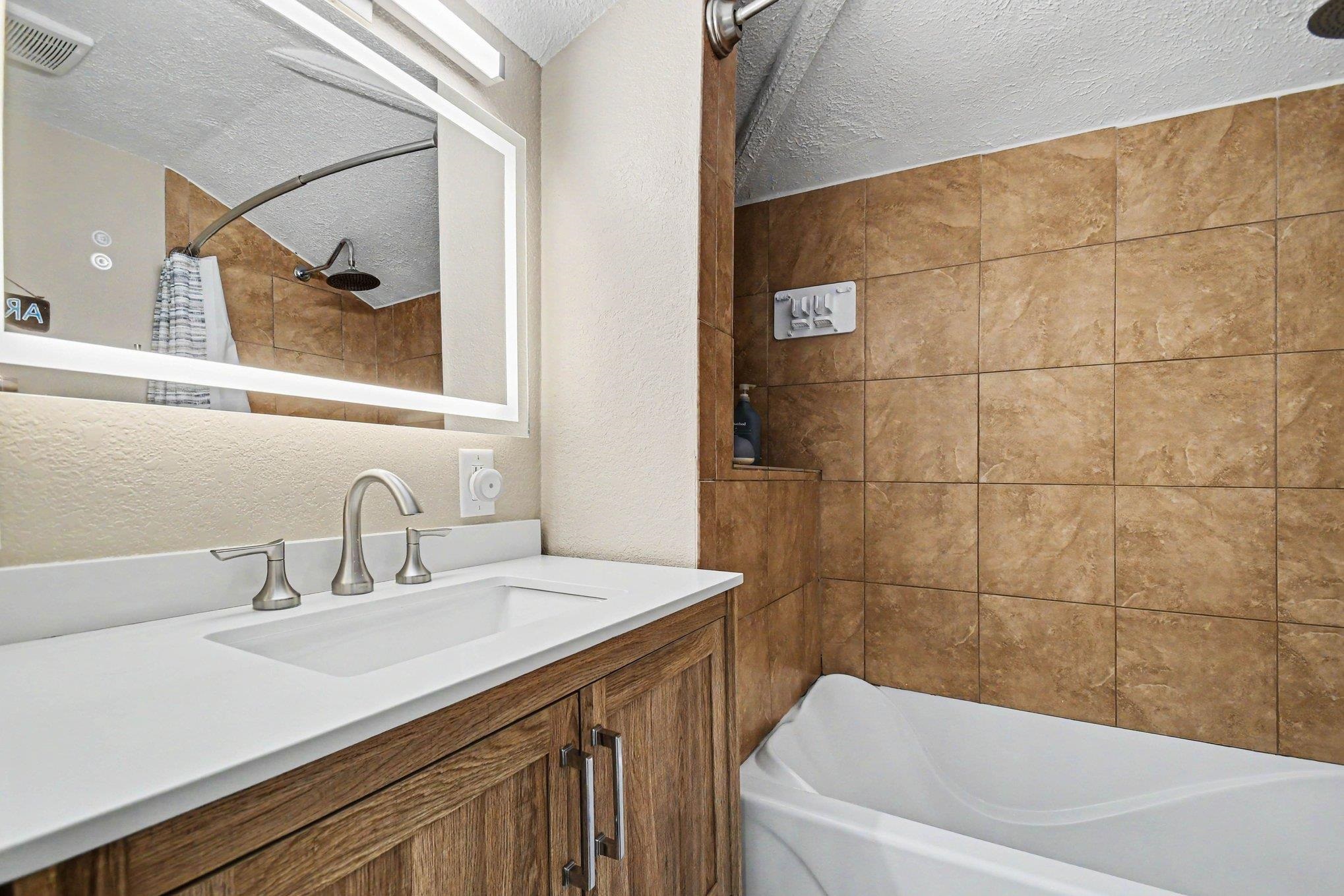 Bathroom featuring a wood-finish vanity with an integrated sink, a white countertop, and brushed nickel fixtures