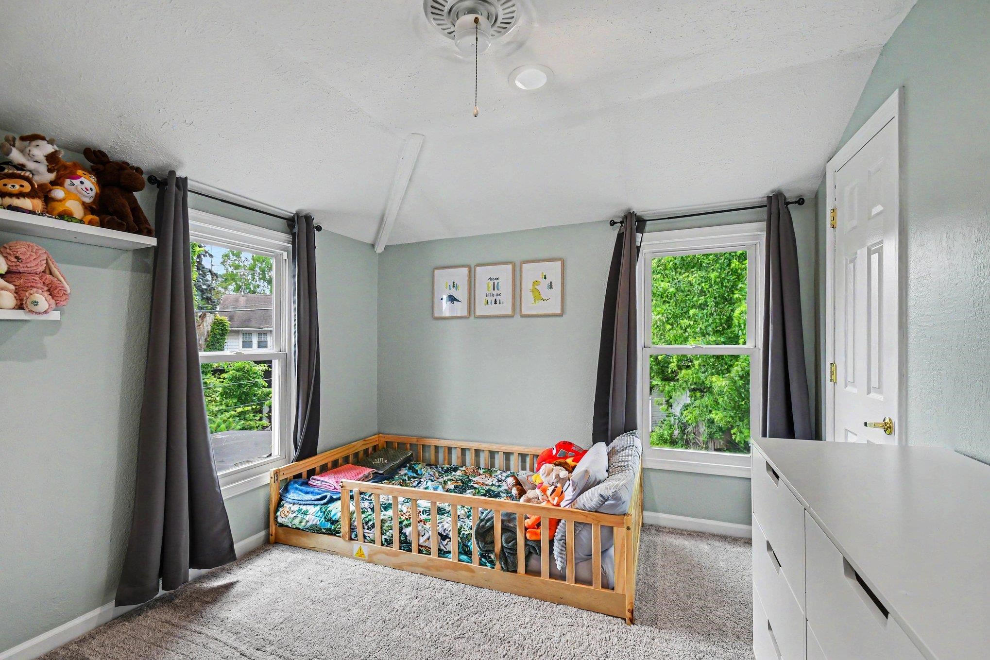 Carpeted room featuring two double-hung windows, a white paneled door with brass hardware, and painted walls