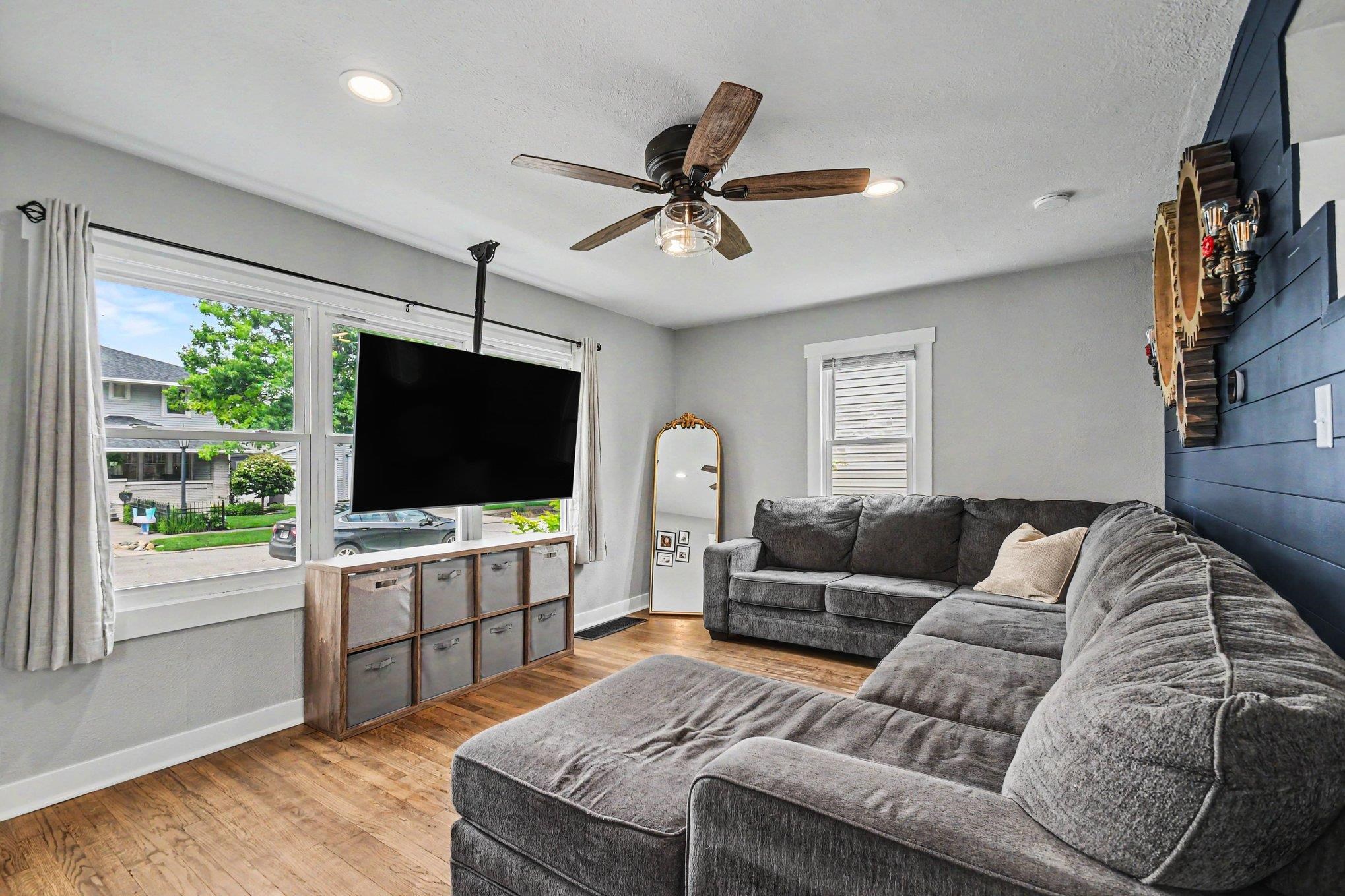Living area featuring wood-finish flooring, recessed lighting, and a ceiling fan with light fixture