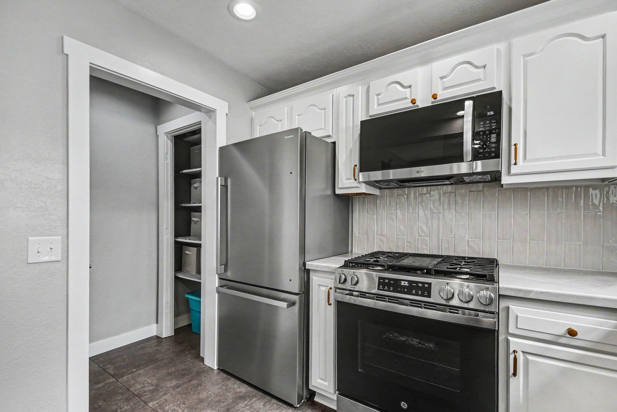 Kitchen featuring white cabinetry, stainless steel appliances, a tile backsplash, and recessed lighting