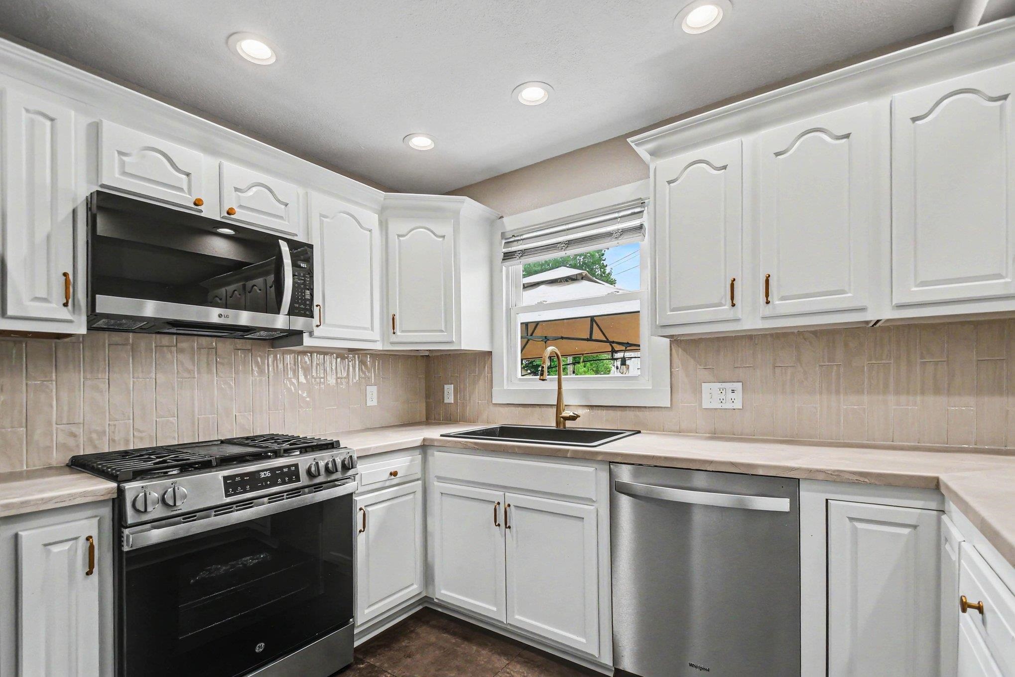 Kitchen featuring white cabinetry, light-toned countertops, and a tiled backsplash