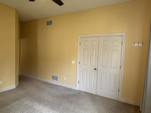 Carpeted room featuring a ceiling fan, bifold closet doors, and light yellow painted walls