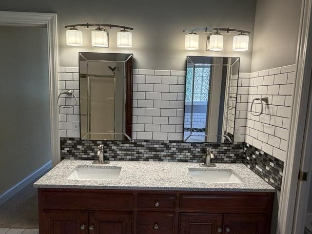 Double vanity featuring integrated sinks set in a speckled countertop, a mosaic tile backsplash, and two framed mirrors