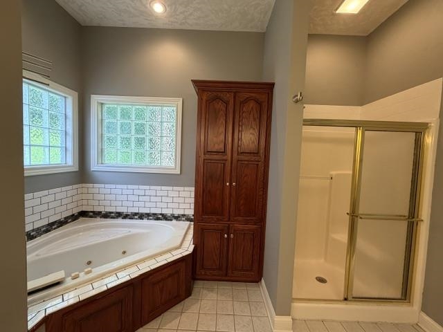 Corner jetted tub with subway tile surround, two glass block windows, a tall built-in wood-finish cabinet, and a stand-up shower with a sliding glass door