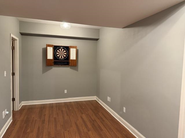 Recreation area featuring a built-in dartboard cabinet, wood-finish flooring, and light gray walls with white trim