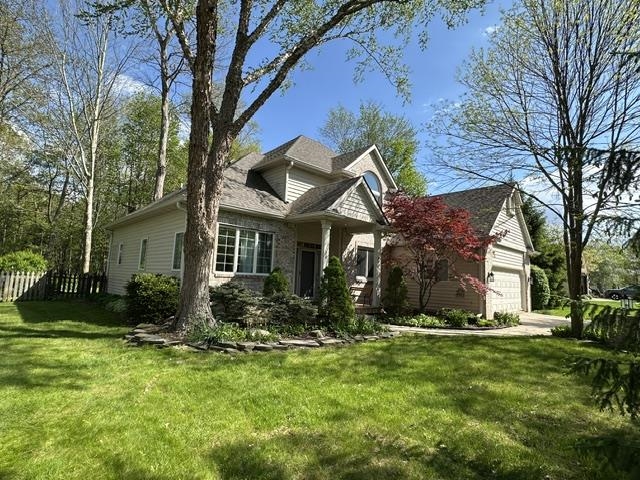 Spacious residence featuring a stone and siding exterior, an attached two-car garage, and a gabled roof