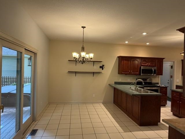 Spacious kitchen and dining area featuring ceramic tile flooring, dark wood cabinetry, and stainless steel appliances