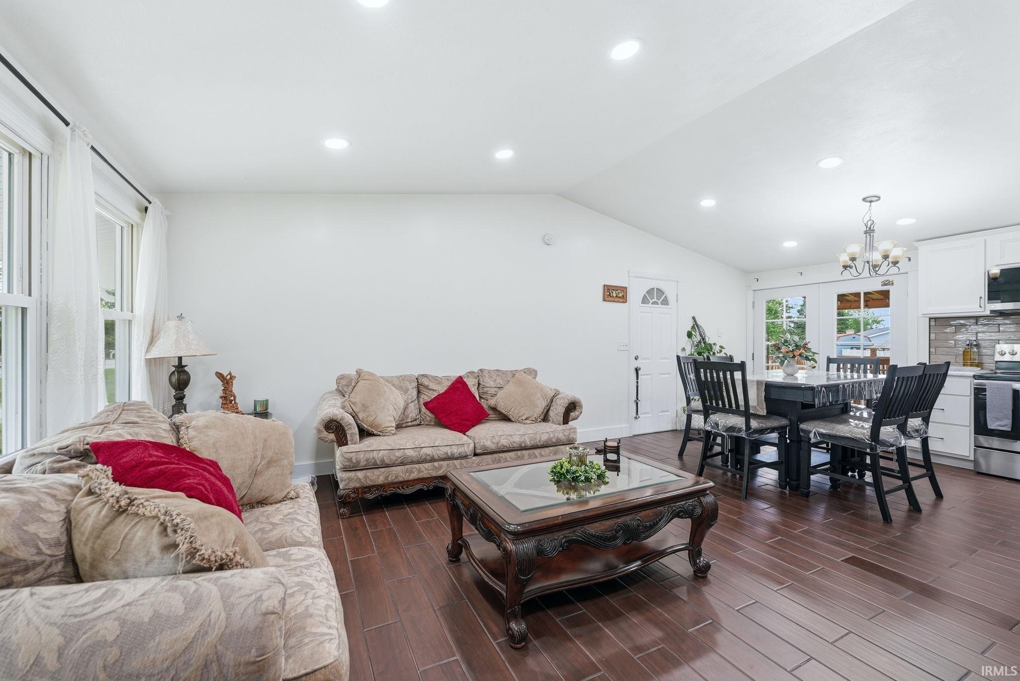Open-concept living space featuring high vaulted ceilings, recessed lighting, and wood-finish flooring throughout