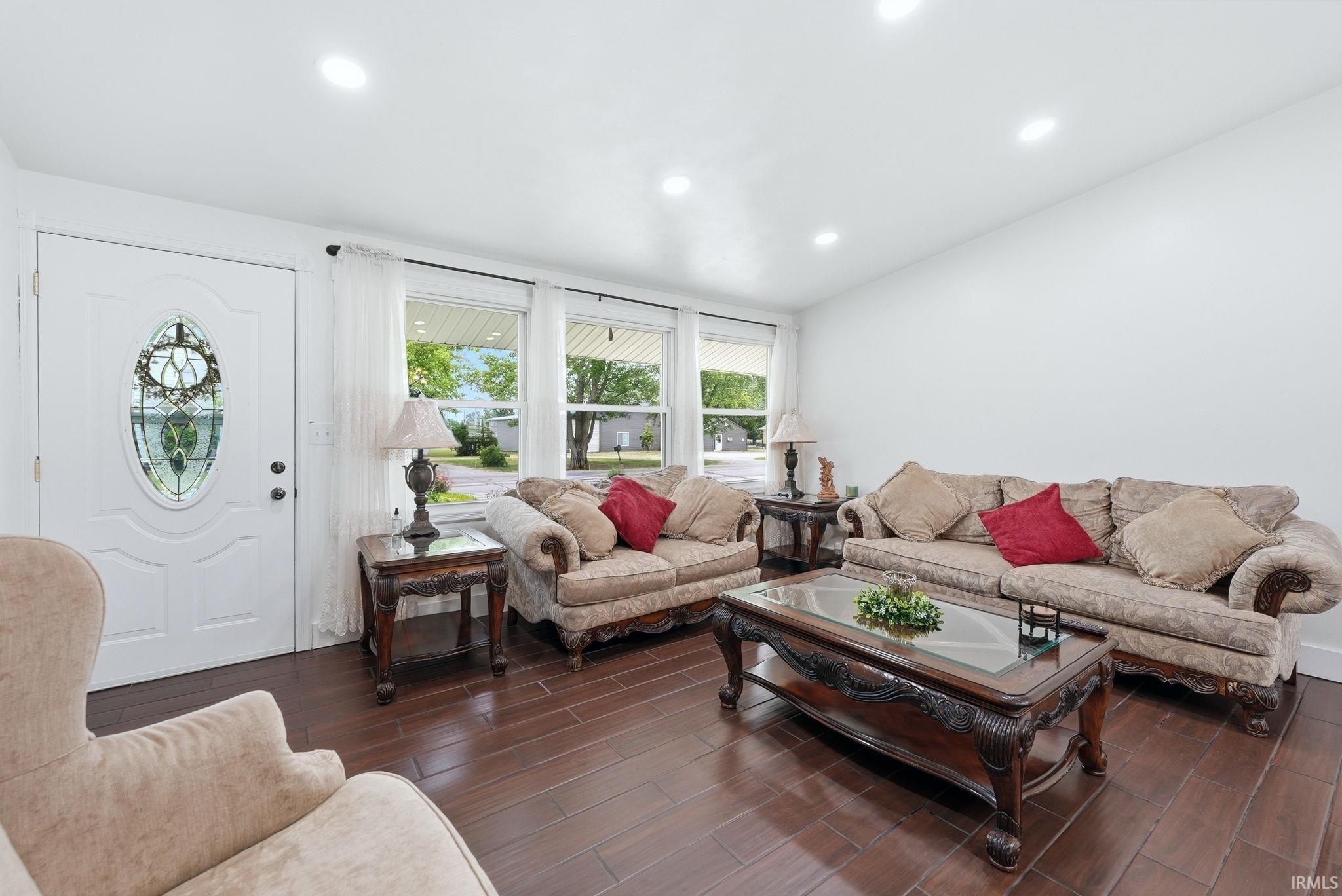 Living area featuring wood-finish flooring, recessed lighting, and multiple windows with white curtains
