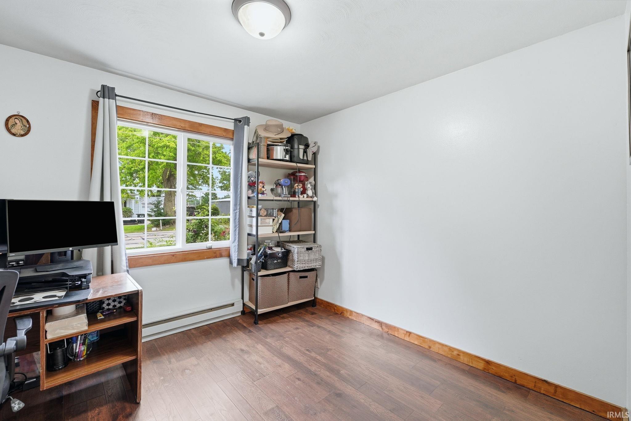 Room featuring wood-finish flooring, a double-hung window with a wooden frame, and a flush mount ceiling light