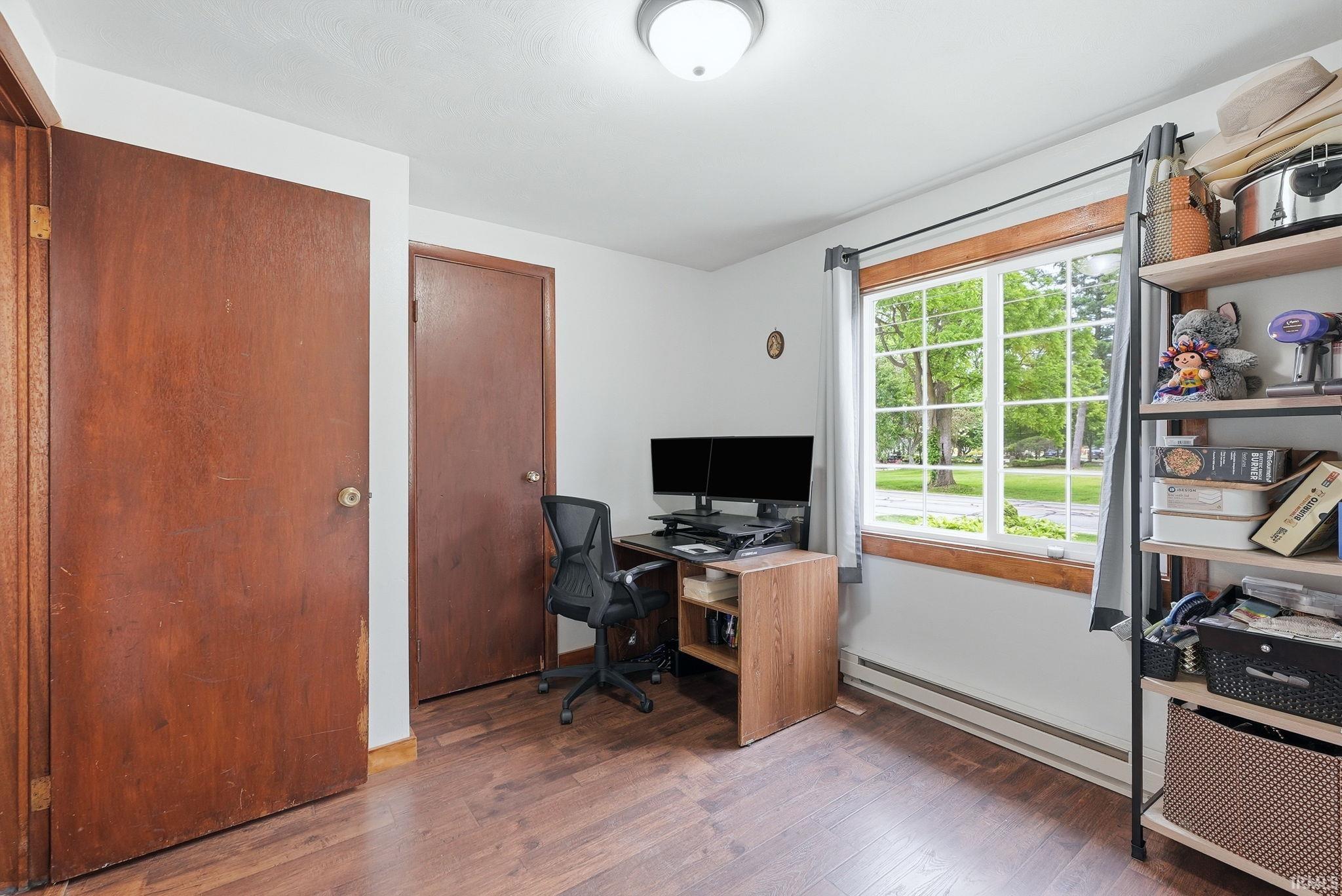 Room featuring wood-finish flooring, white walls, and two wood panel doors