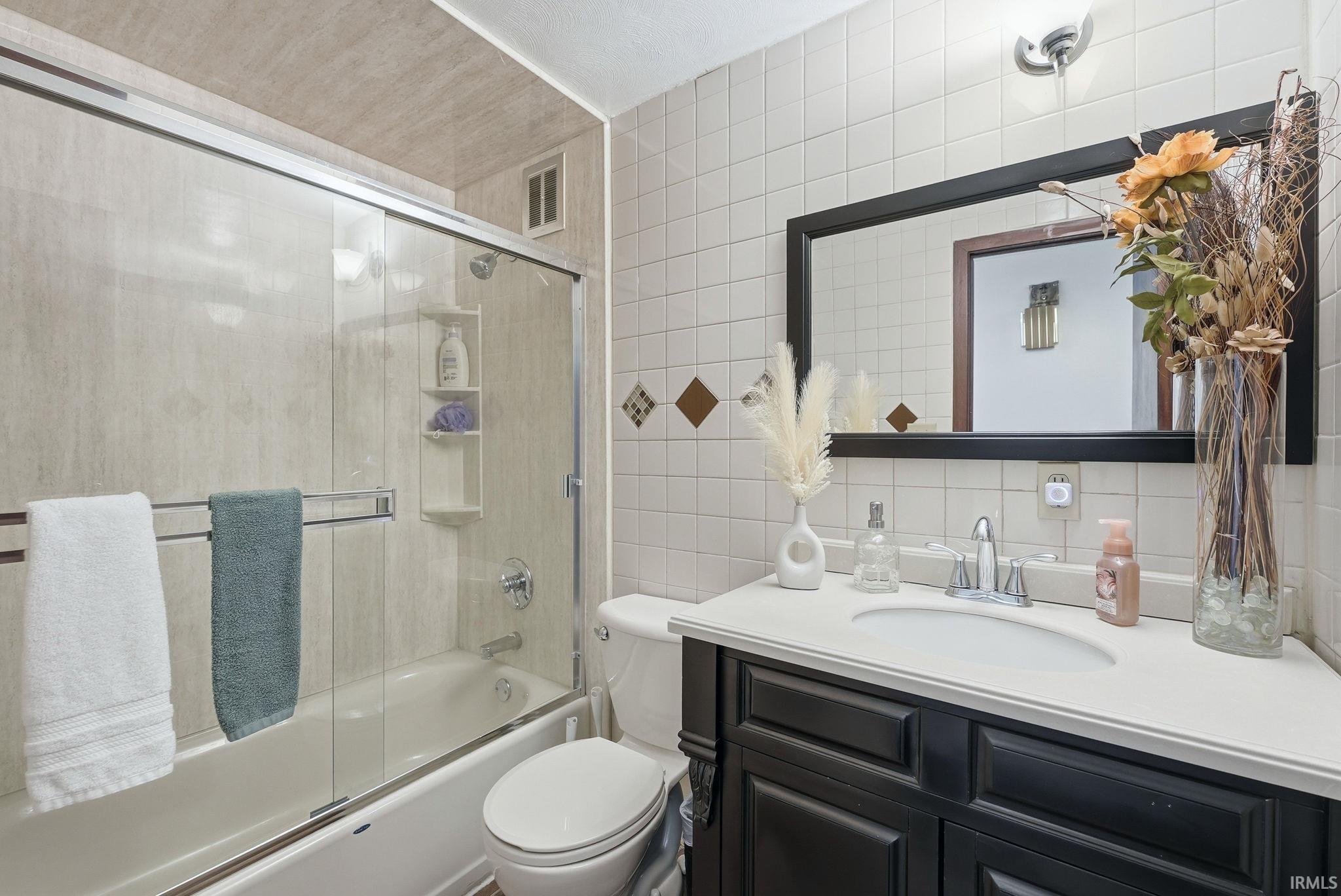 Bathroom featuring a dark wood-finish vanity with a white countertop, an integrated sink, and a framed mirror
