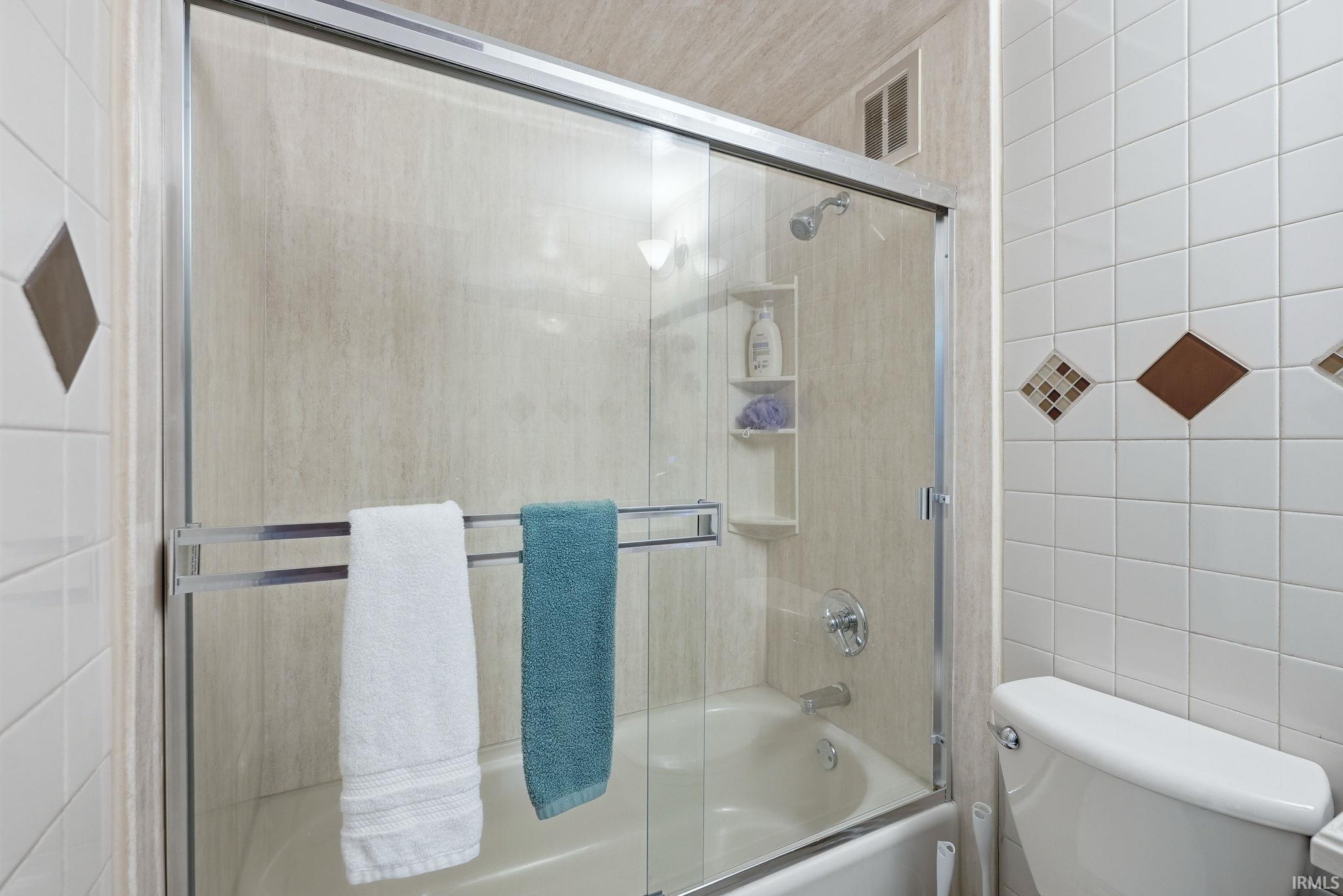 Bathtub with sliding glass enclosure, integrated shower head, and built-in shelving