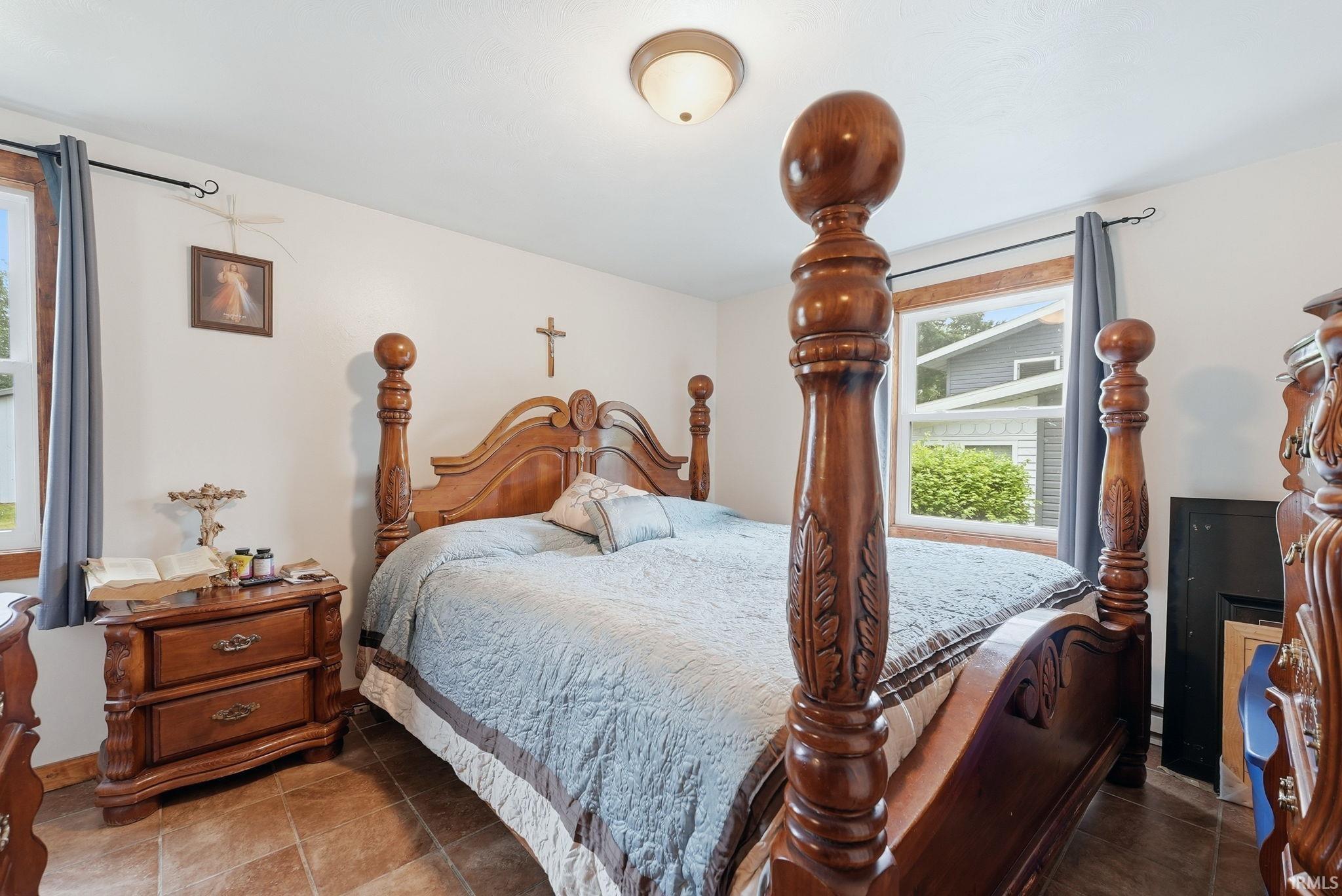 Spacious room featuring neutral wall tones, two windows with wood trim, a semi-flush mount ceiling light, and durable tile flooring