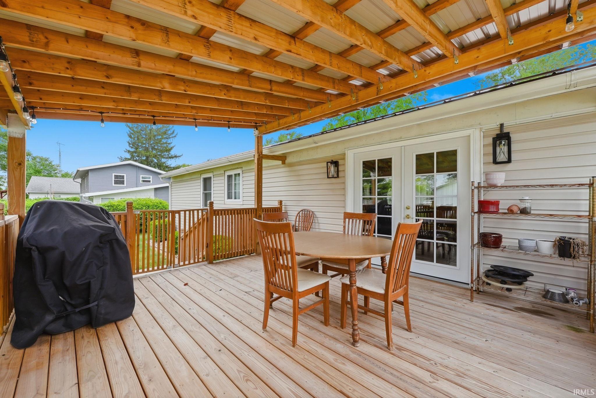 Expansive wood-finish deck with a covered patio featuring a metal roof and exposed wood beams