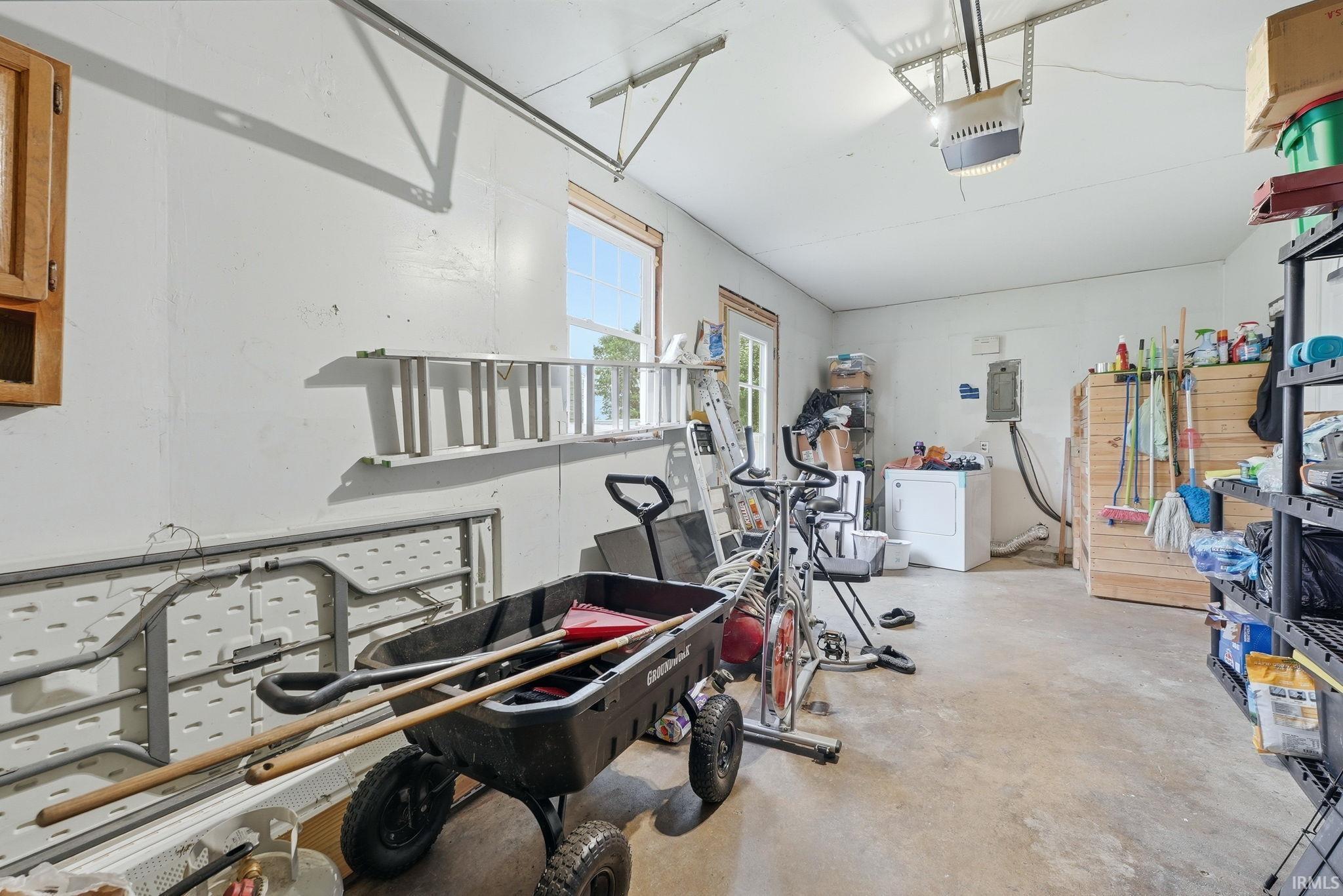 Spacious garage featuring a concrete floor, overhead garage door system, exterior window, and a service door