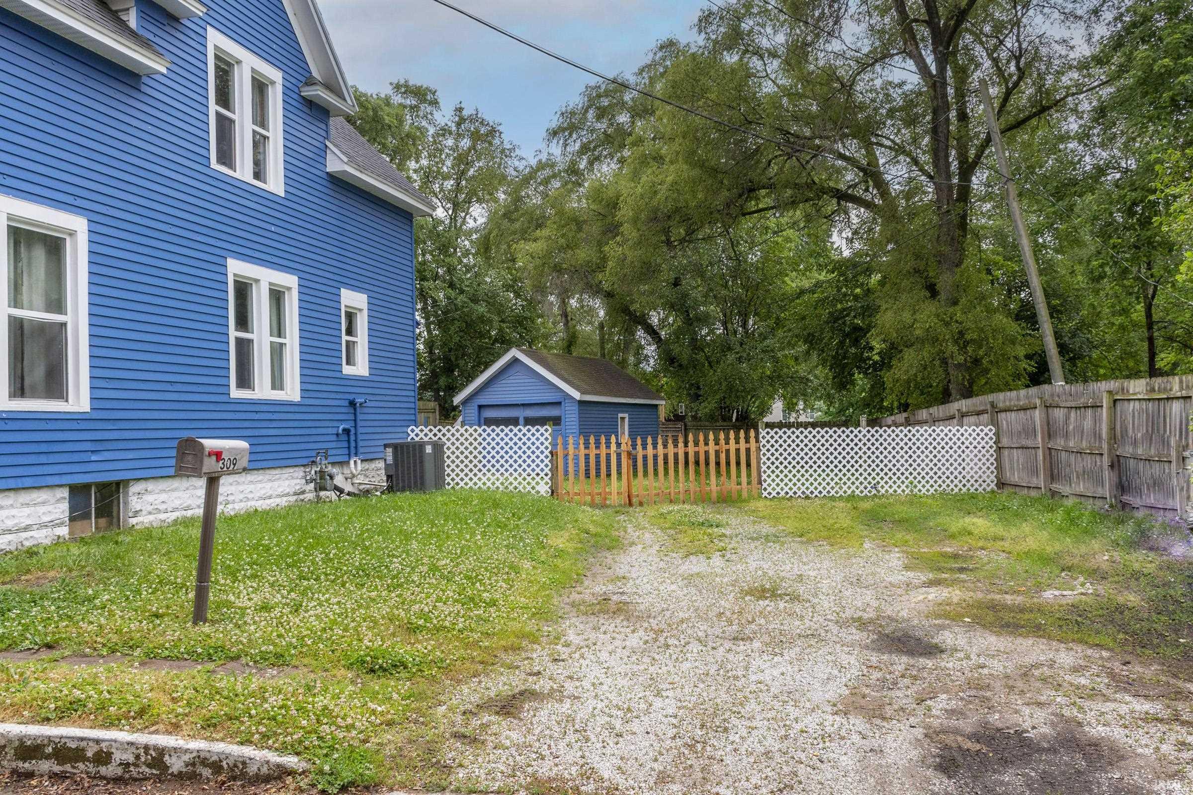 Blue siding exterior with white trim windows and a gravel driveway