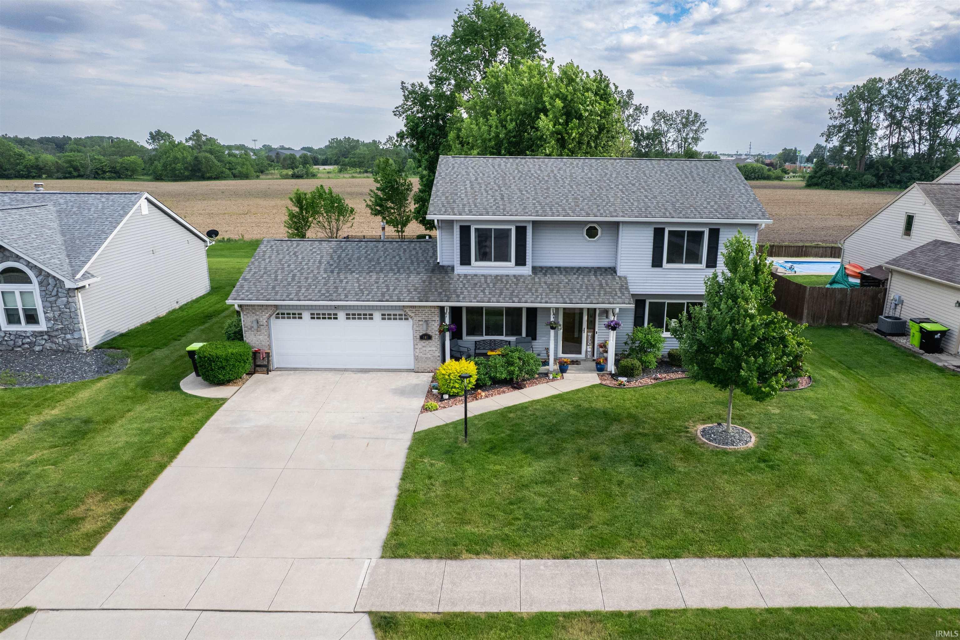 Two-story residence featuring light gray siding, dark shutters, and a covered front porch