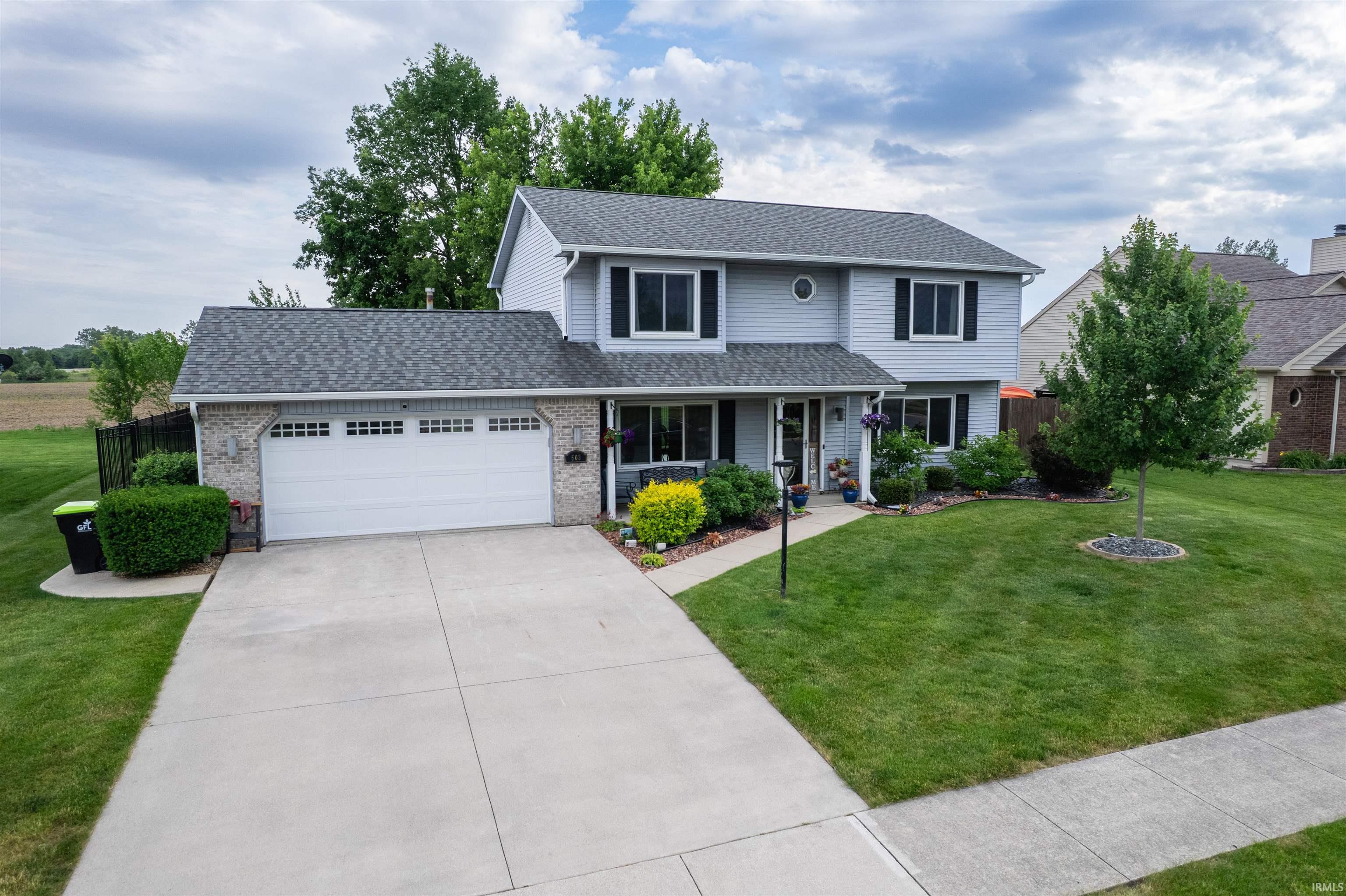 Two-story home featuring light grey siding, dark shutters, and a grey shingle roof