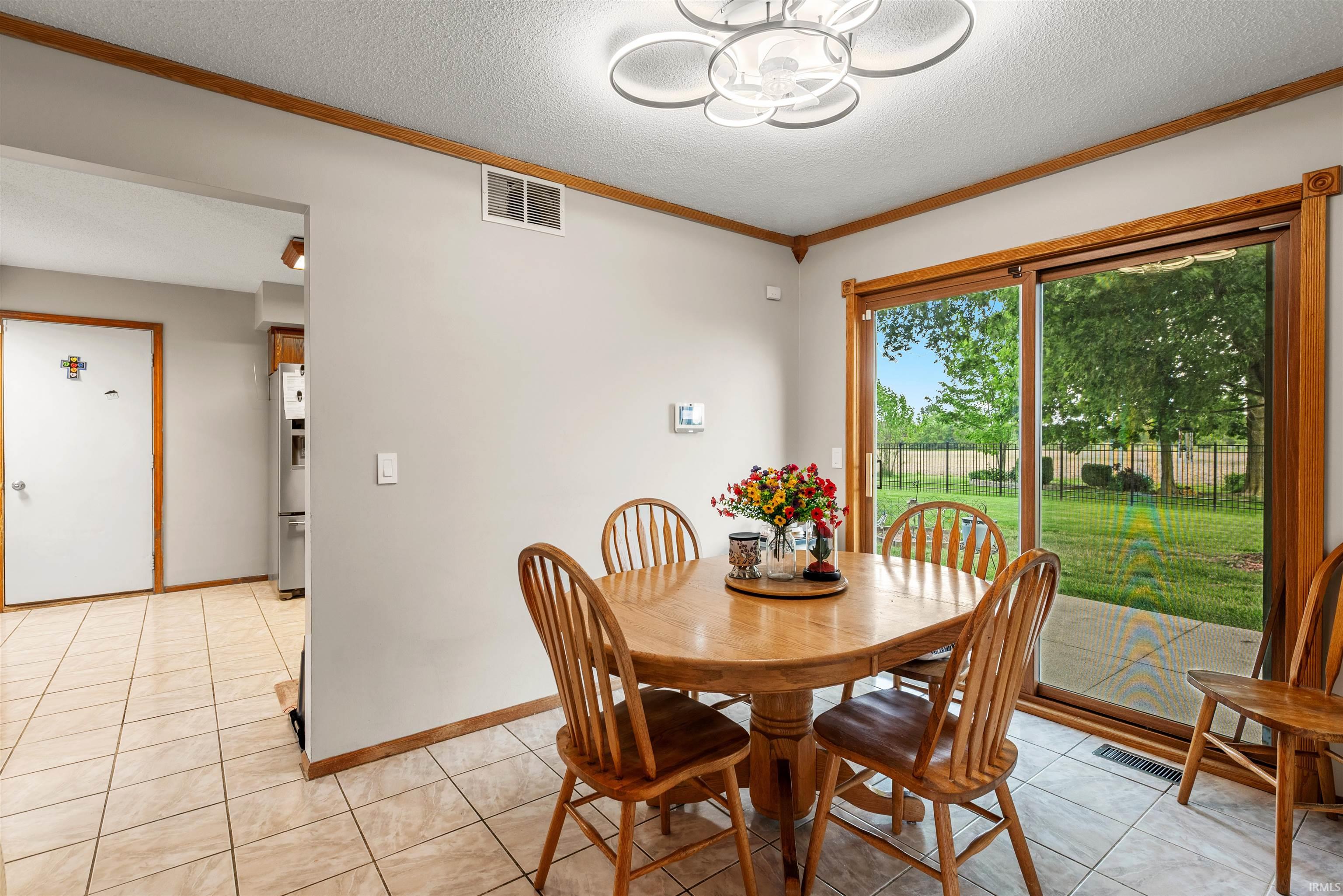 Dining area featuring tile flooring, a contemporary ceiling light fixture, and wooden trim