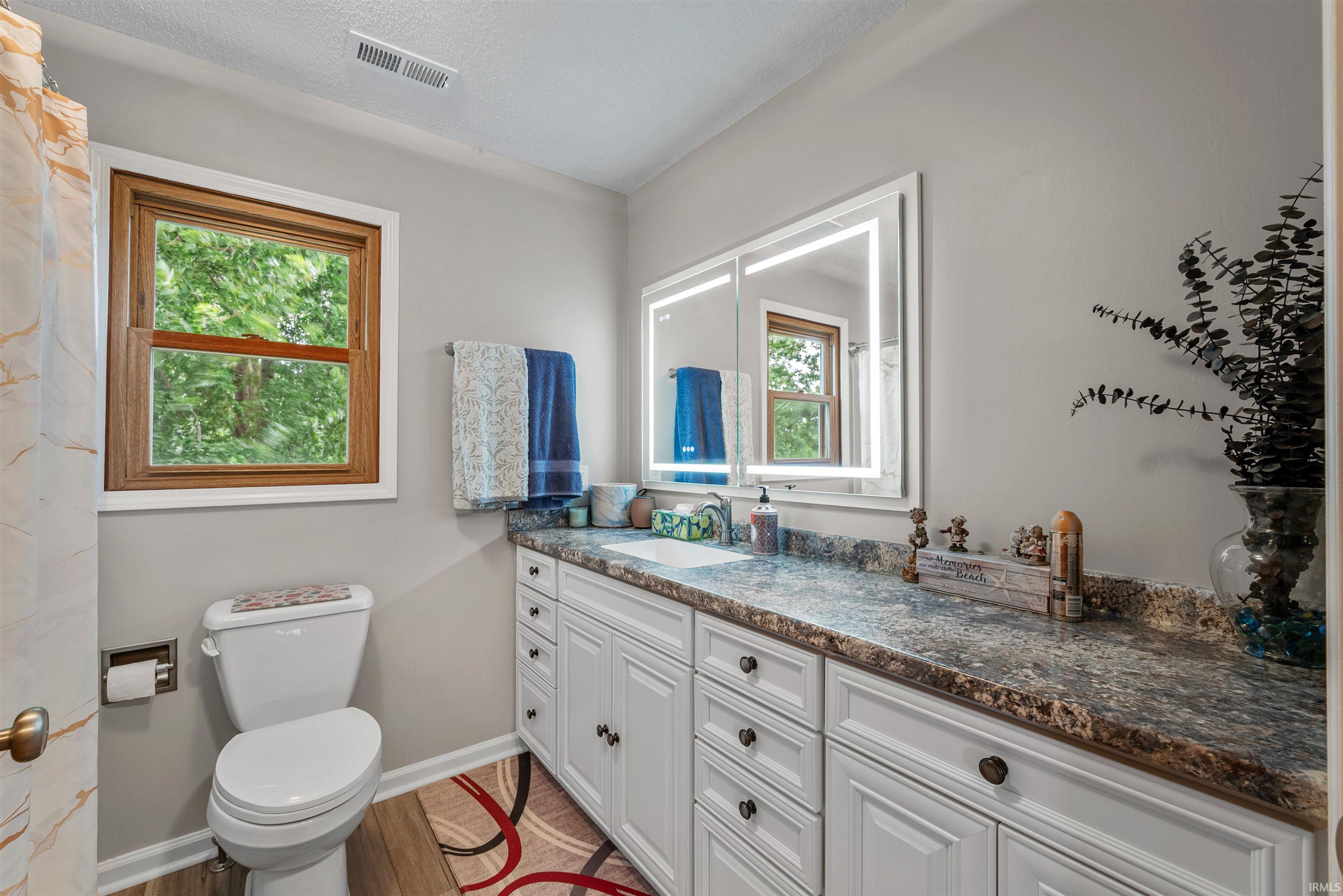Vanity featuring a built-in sink, white cabinetry with dark hardware, and a granite-look countertop