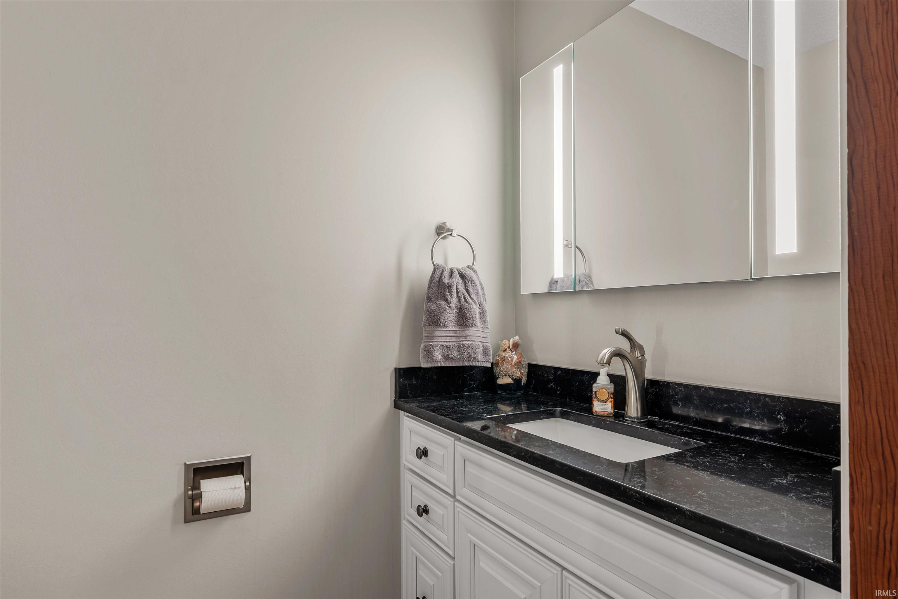 Bathroom vanity featuring a recessed sink, dark countertop, and brushed nickel fixtures