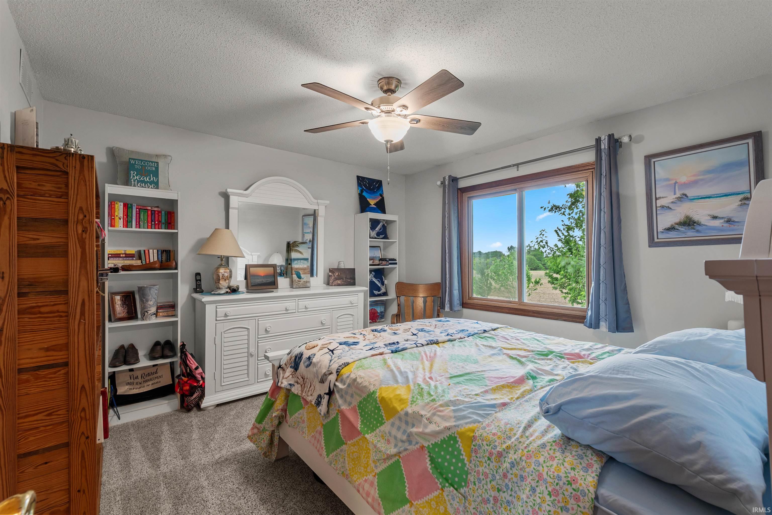 Room featuring a large window with wood-finish trim, a ceiling fan with integrated lighting, and neutral carpeting