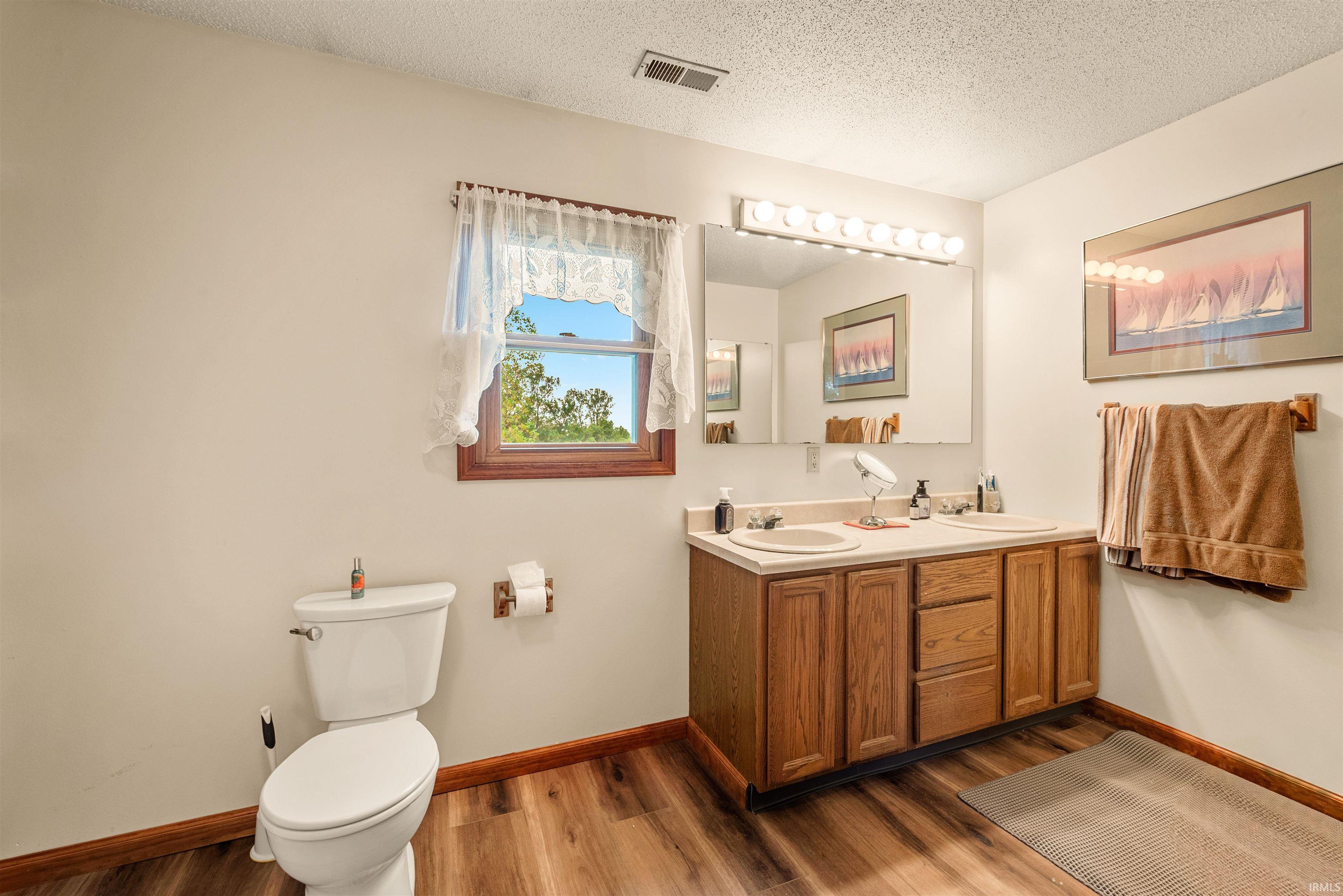 Bathroom featuring a double vanity with light wood cabinetry, dual sinks, and a large mirror