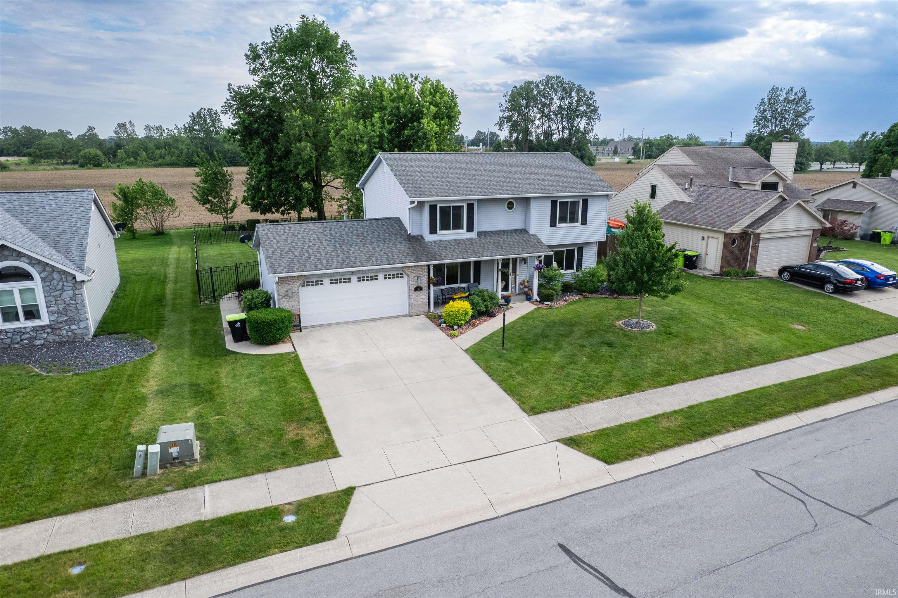 Two-story residence featuring a two-car garage, concrete driveway, and established front landscaping