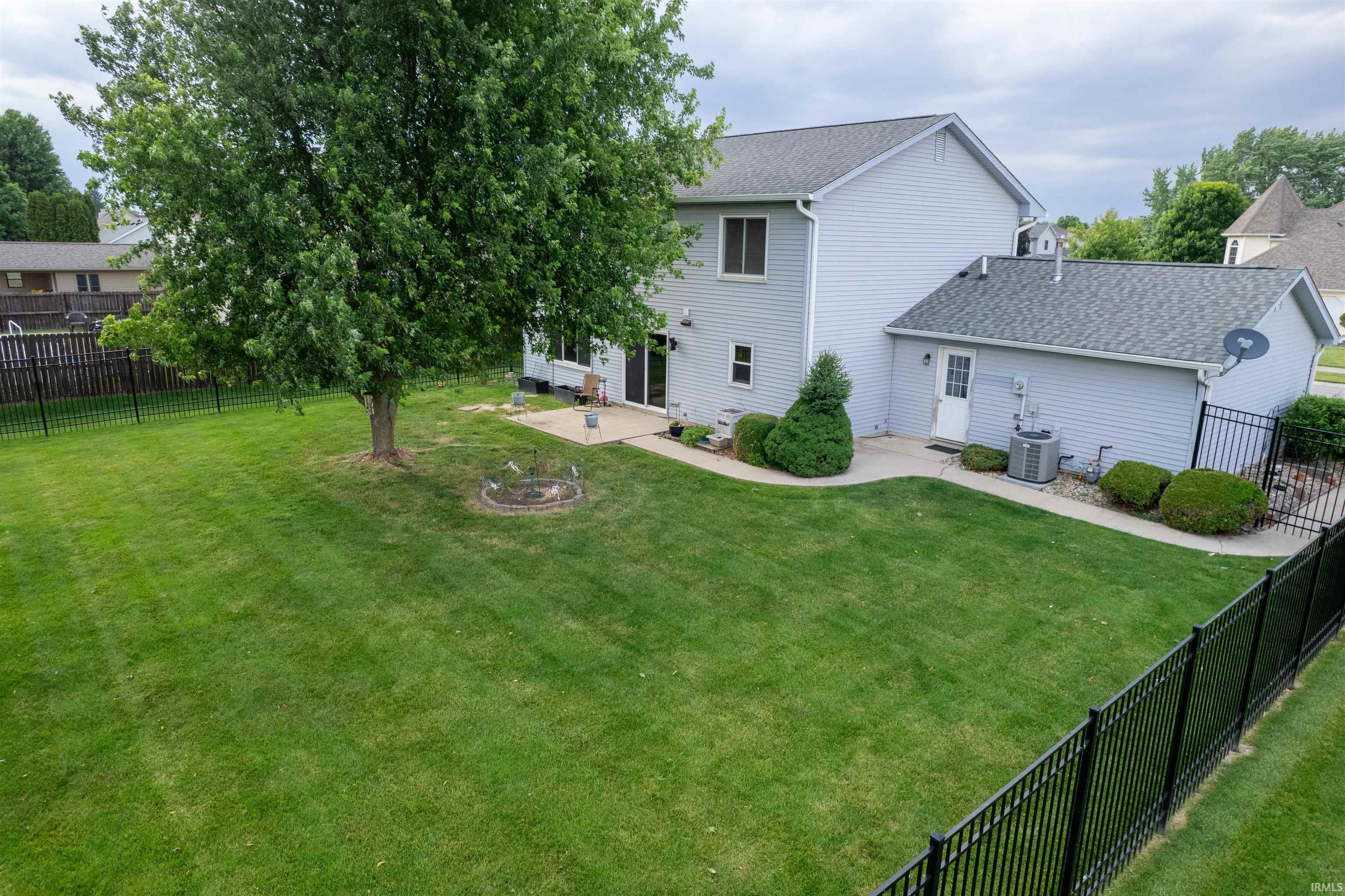 Expansive green lawn with a mature tree, bordered by a black metal fence
