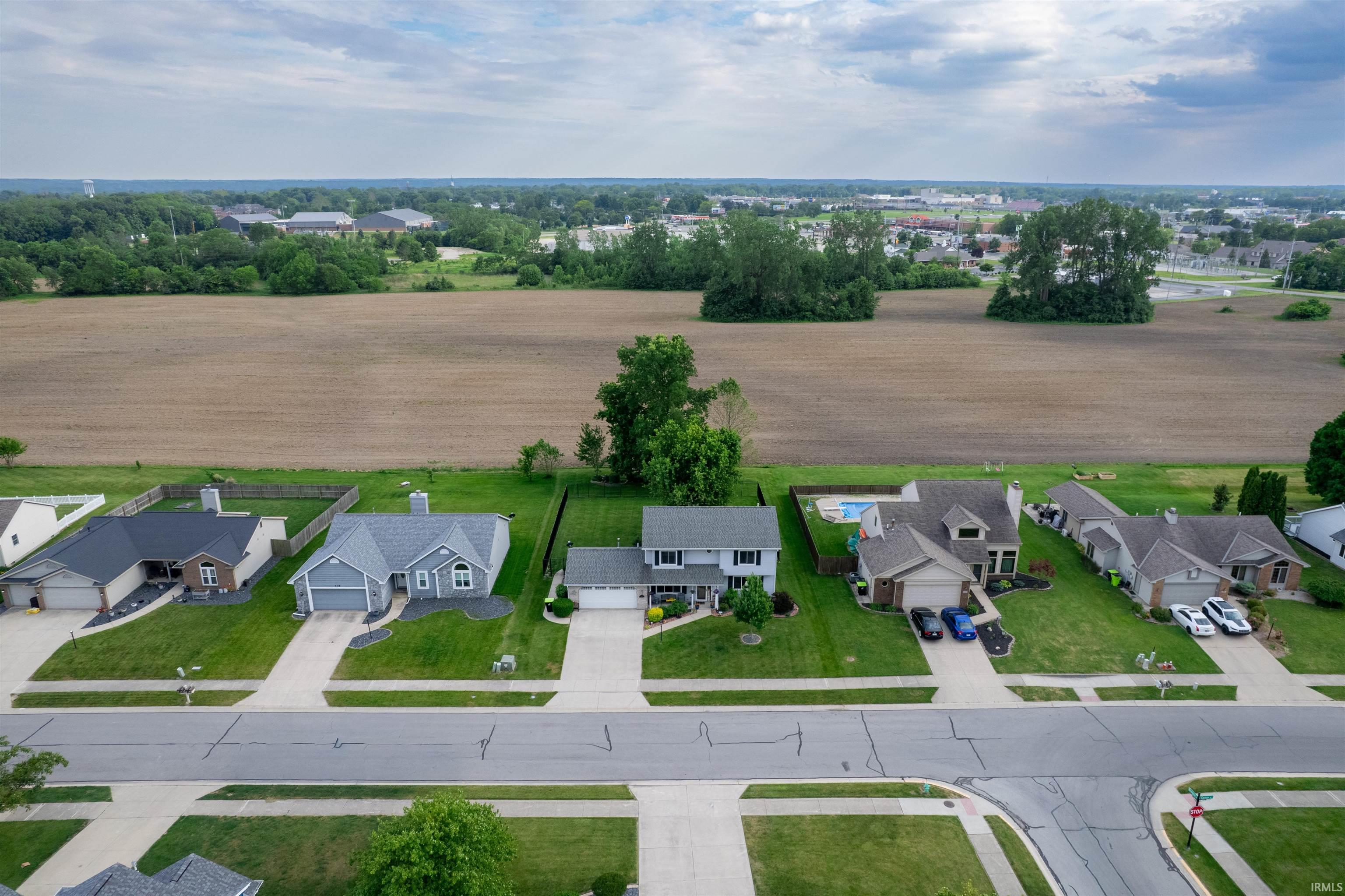 Residential street with asphalt roads and concrete sidewalks, featuring multiple single-family homes with green lawns and established landscaping