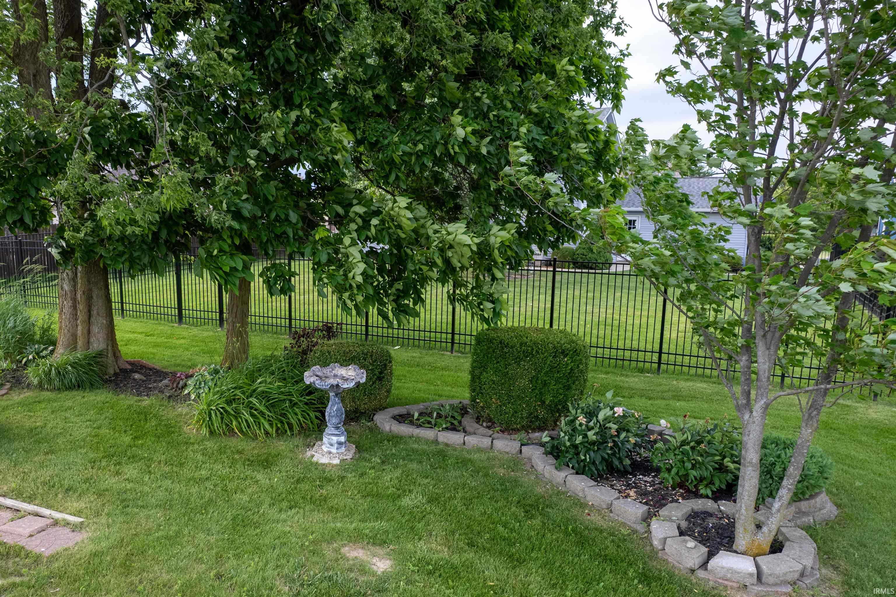 Lush green lawn with mature trees and established landscaping featuring decorative shrubs