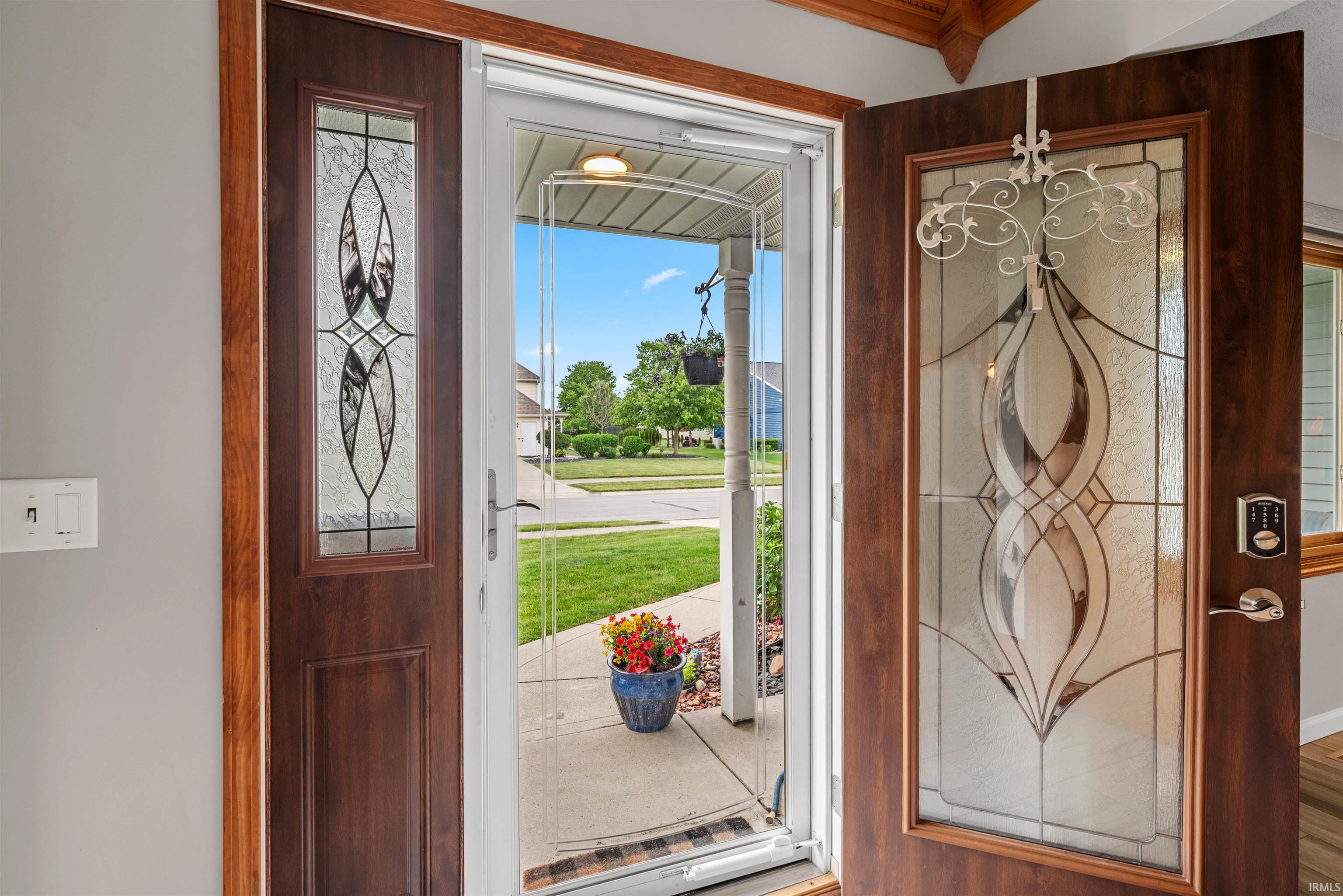 Entryway featuring rich wood-finish doors with decorative leaded glass panels, a full-length storm door, and a digital keyless entry system