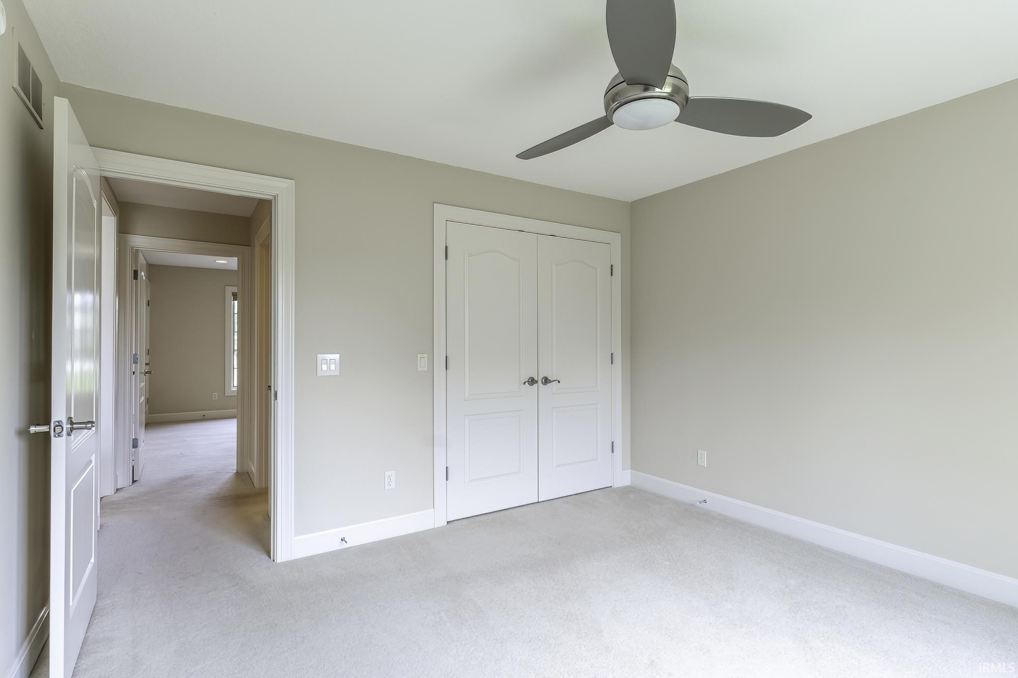 Neutral-toned room featuring a ceiling fan with integrated lighting, carpet flooring, and white trim throughout