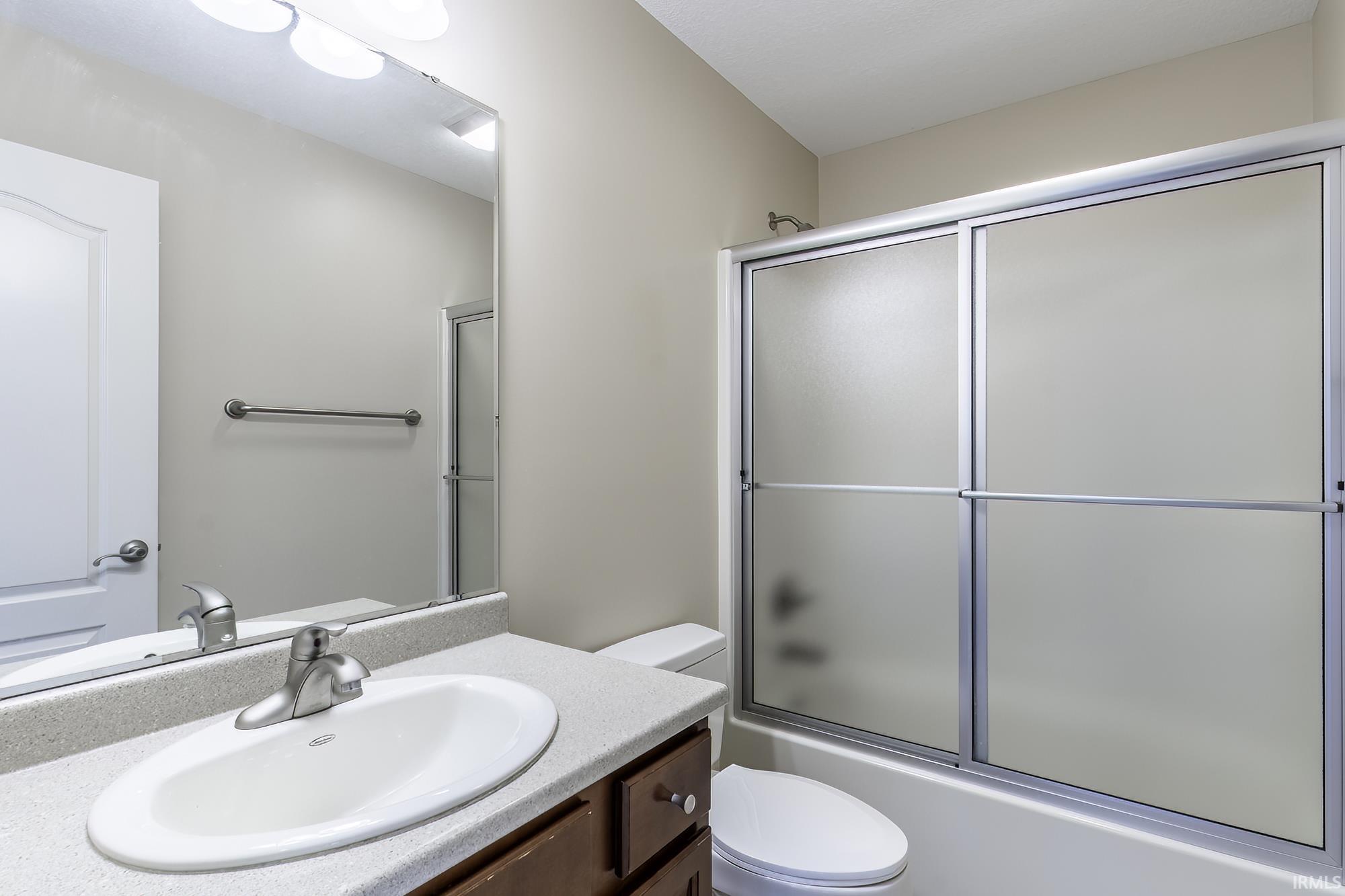 Bathroom featuring a vanity with an oval sink, brushed nickel faucet, and a light-toned countertop