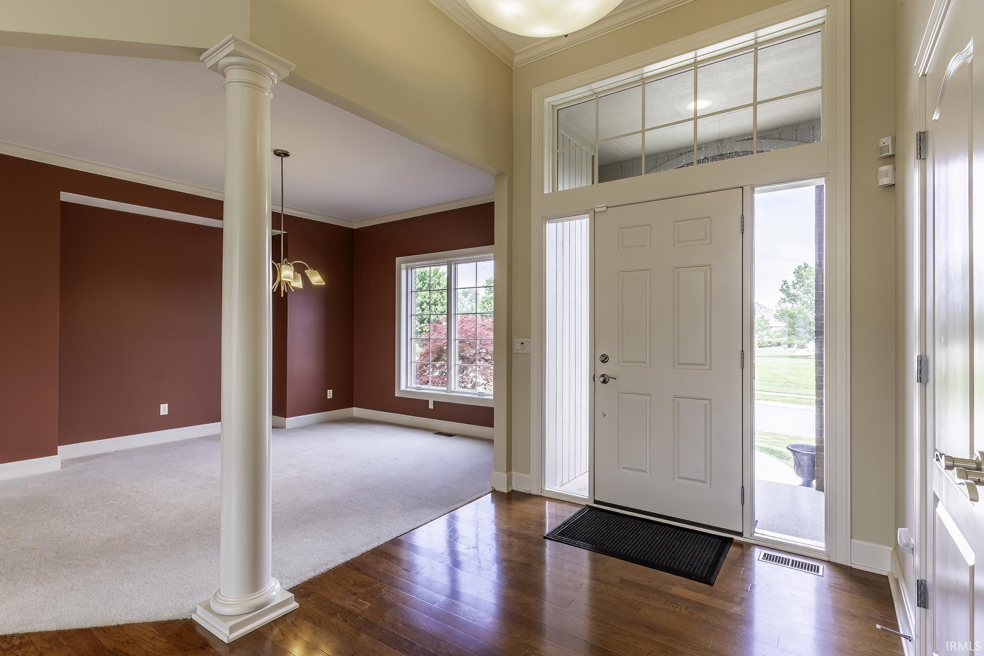Entry foyer with wood-finish flooring and a white six-panel door with sidelights and transom window