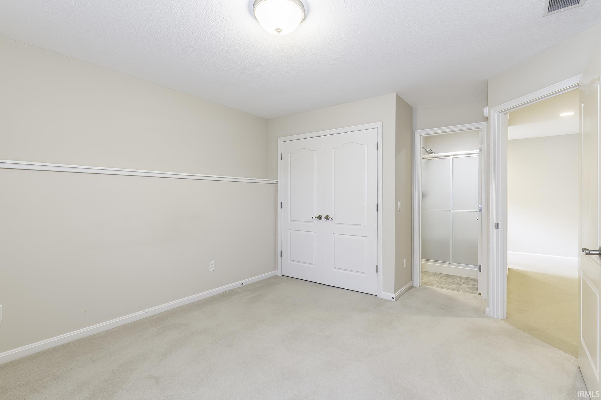 Neutral tone walls with white trim, a double-door closet, recessed lighting, and soft carpet flooring