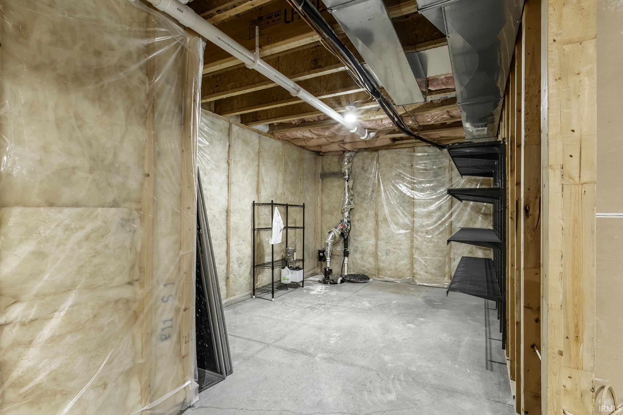Unfinished basement featuring exposed wood joists, concrete flooring, and visible insulation