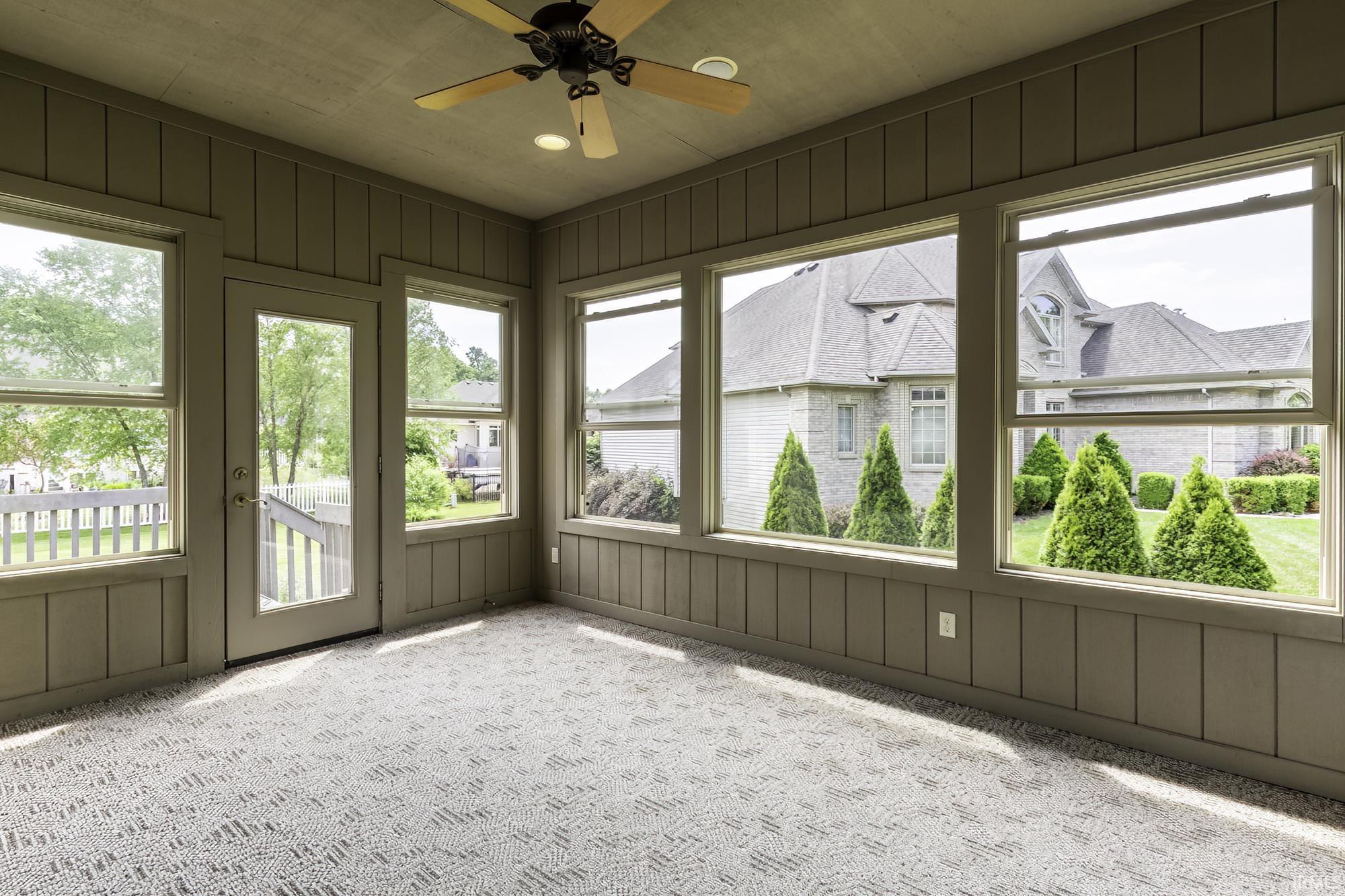 Sun-drenched room featuring multiple windows, a glass-paneled door, and patterned carpet