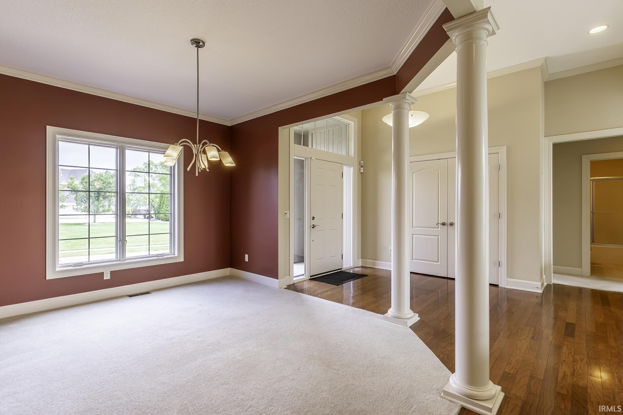 Spacious room featuring a large divided-light window, central chandelier, and light-toned carpeting