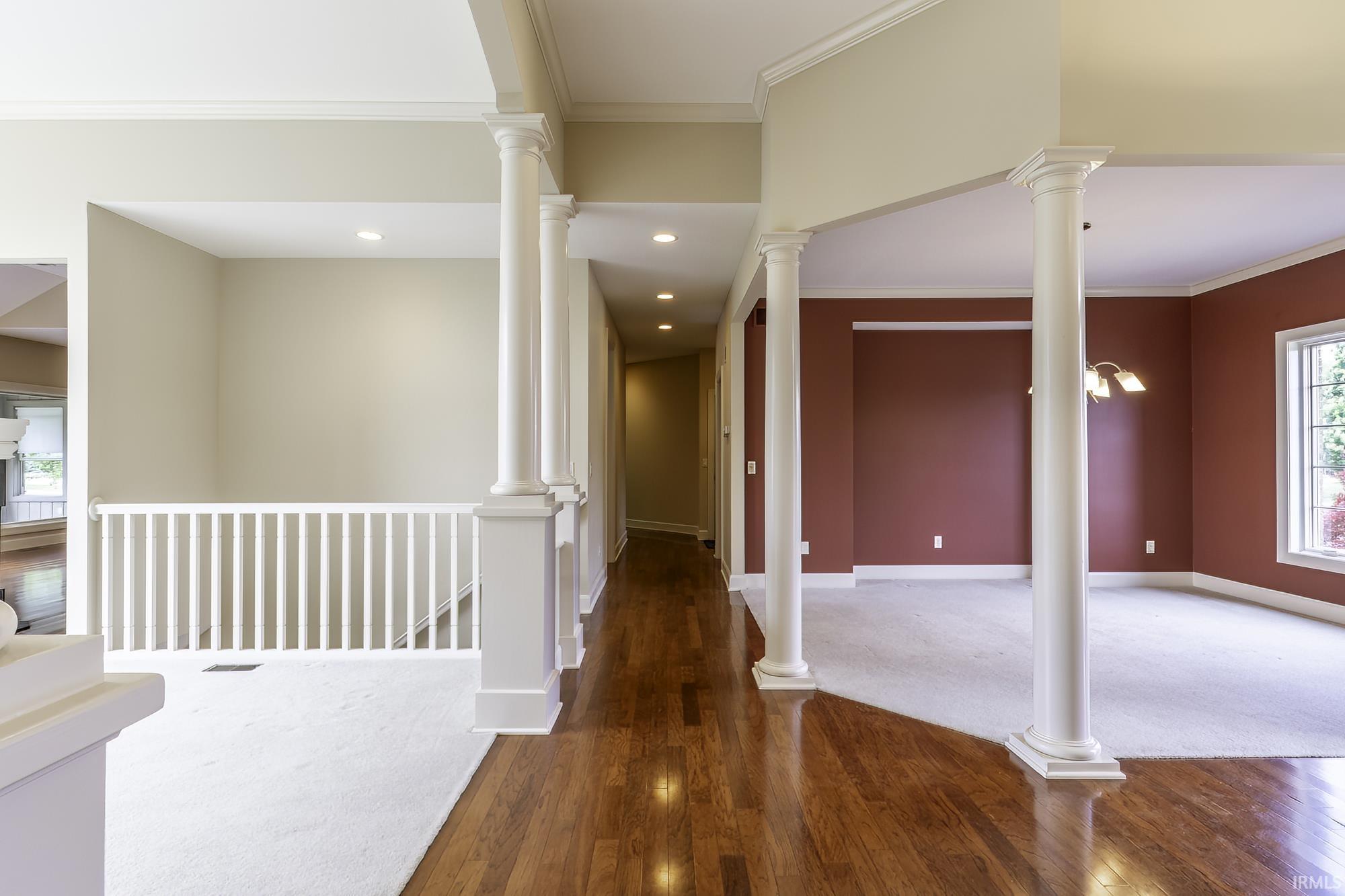 Entryway featuring rich wood-finish flooring, architectural columns, and recessed lighting